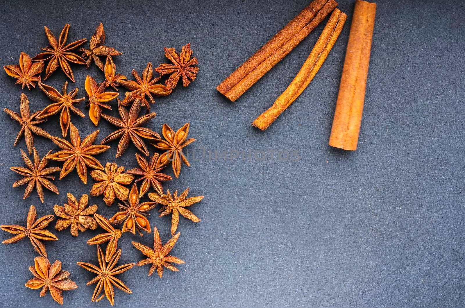 the scattered star anise and cinnamon on slate top view copy spece right