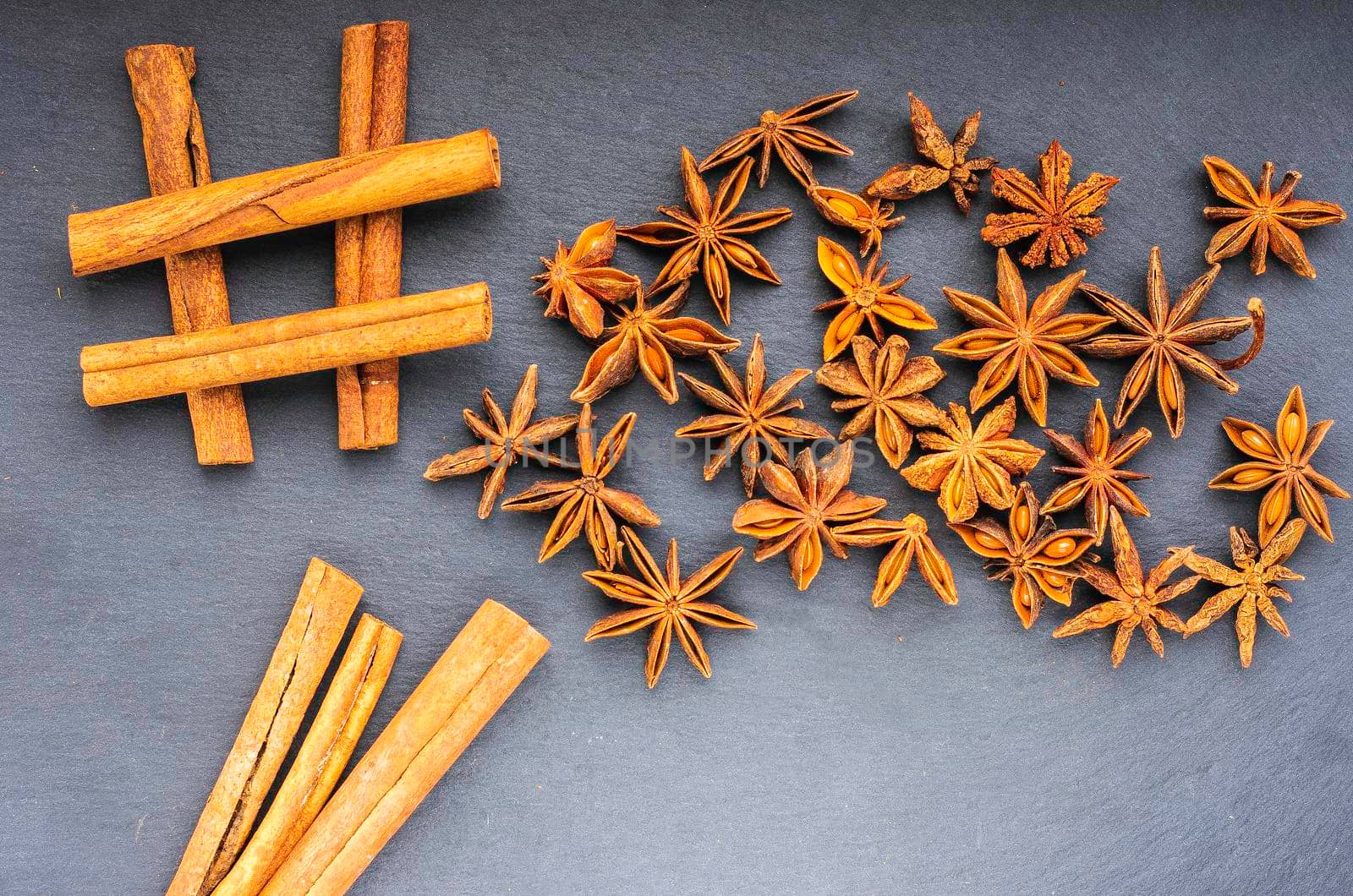 sharp cinnamon and scattered star anise top view on slate.