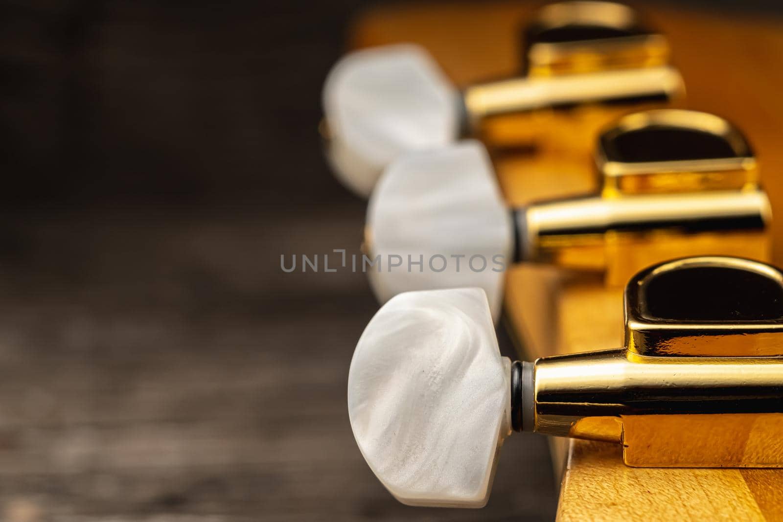 Head of old acoustic golden guitar on wooden. Macro photo. Horizontal orientation