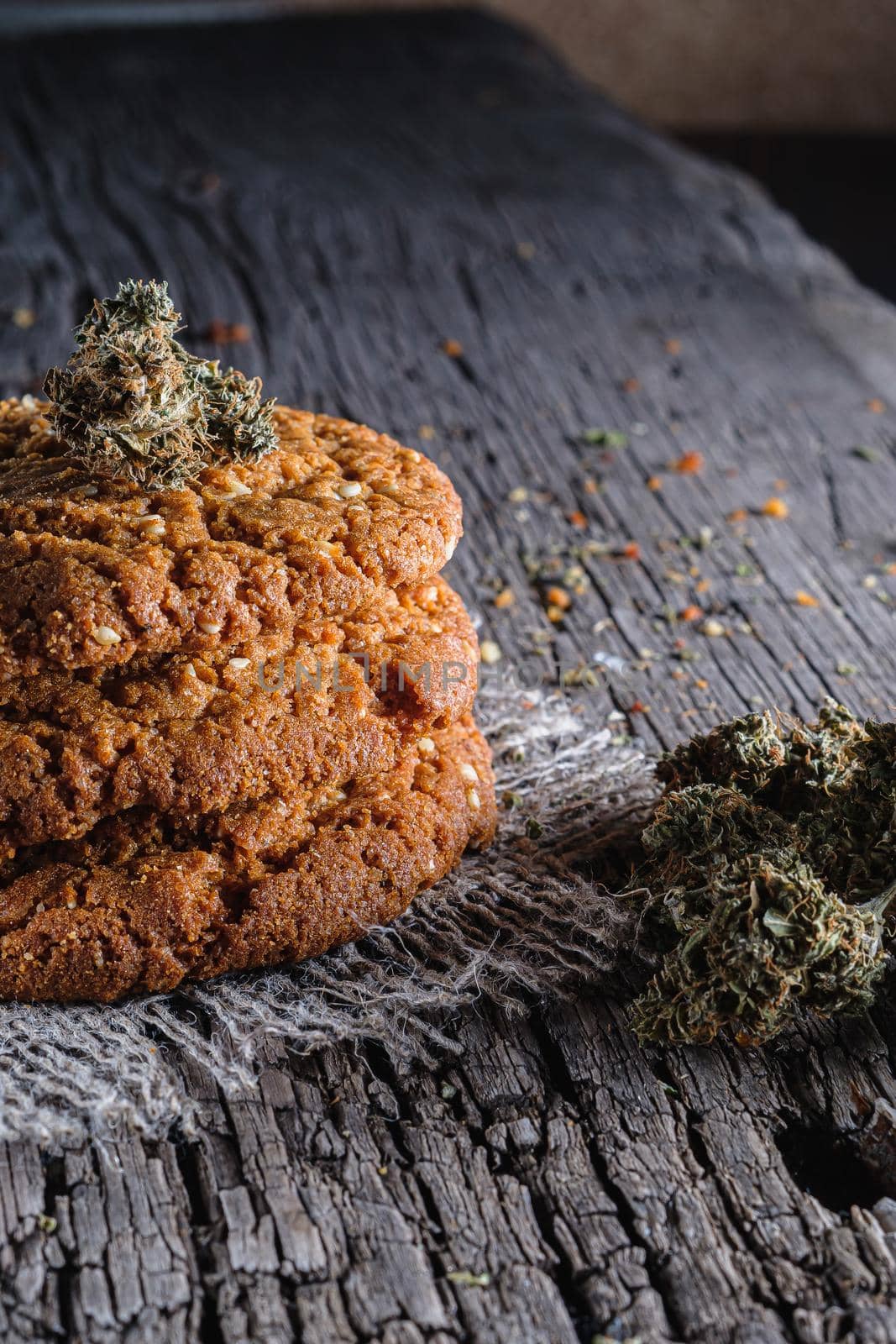 biscuits with marijuana on an old wooden background close-up. Healthy food with medical cannabis. the buds are inaccurately scattered. rustic. Vertical orientation.