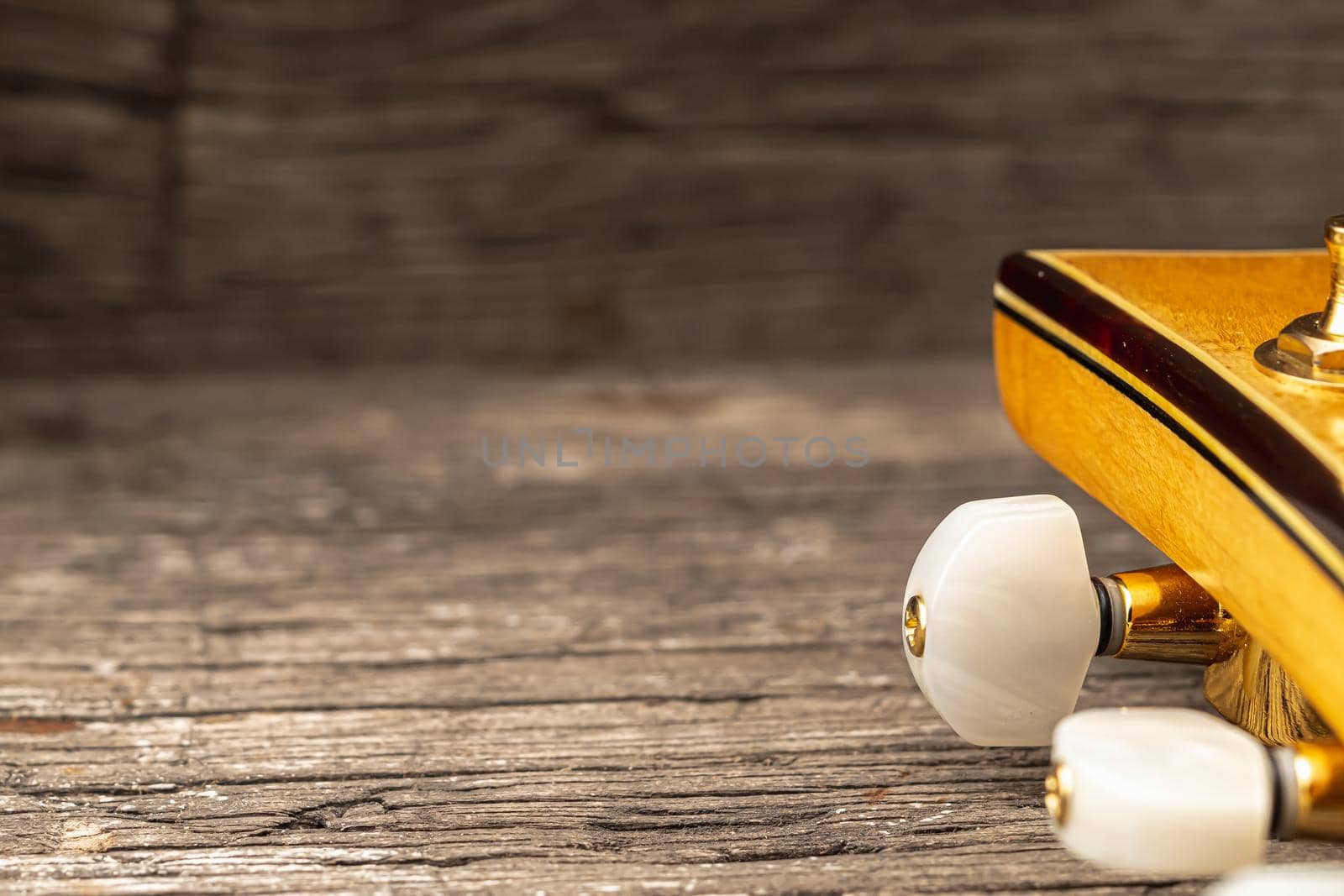 Head of old acoustic golden guitar on wooden. Macro photo. Horizontal orientation