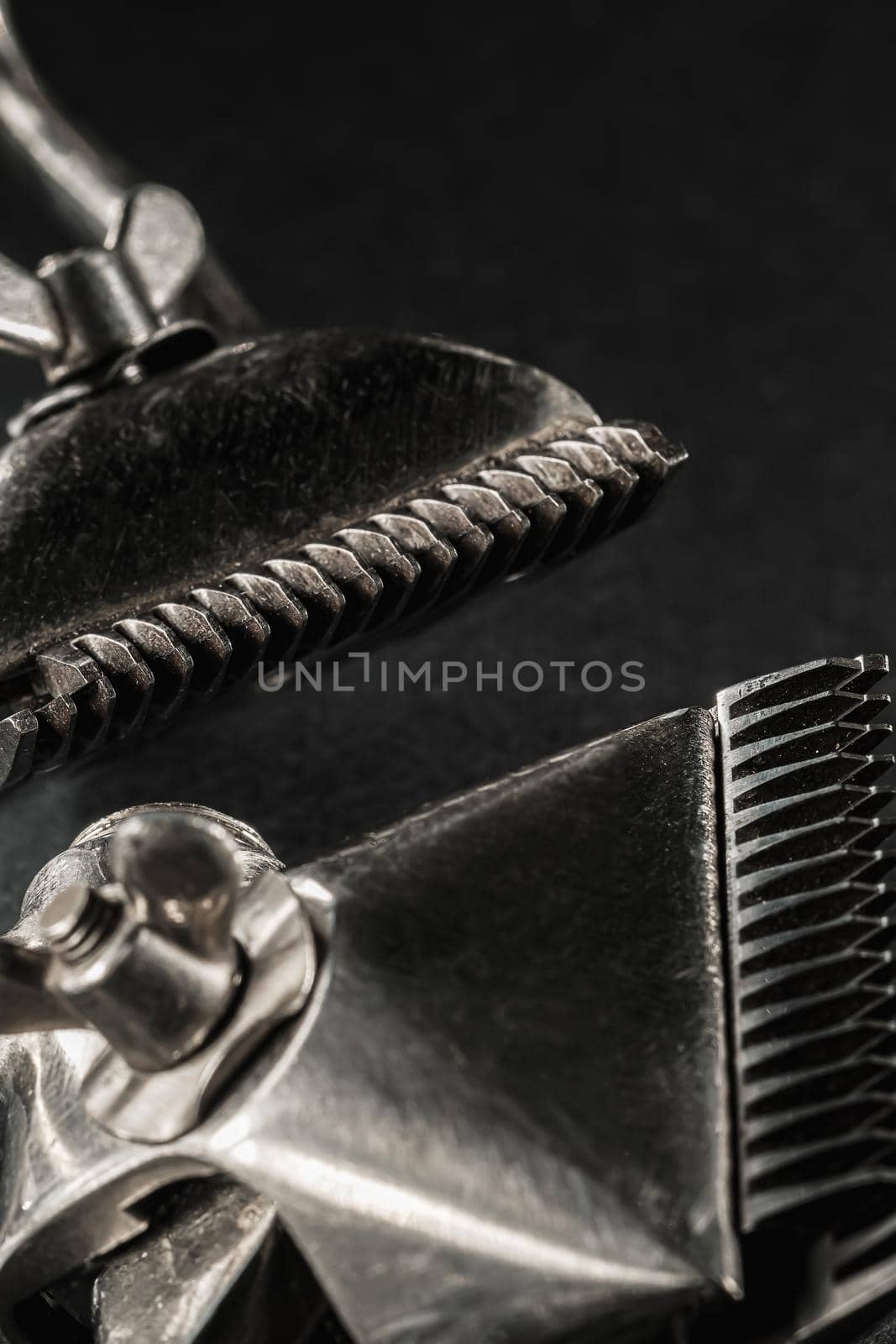 On a black surface are old barber tools.Two vintage manual hair clipper. black monochrome. Close-up. Barbershop background. contrast shadows. vertical orientation