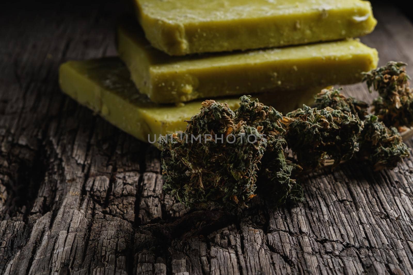 rustic cannabis butter and medical marijuana bud on old rust metal dripping pan. old wooden background. horizontal orientation. close-up.