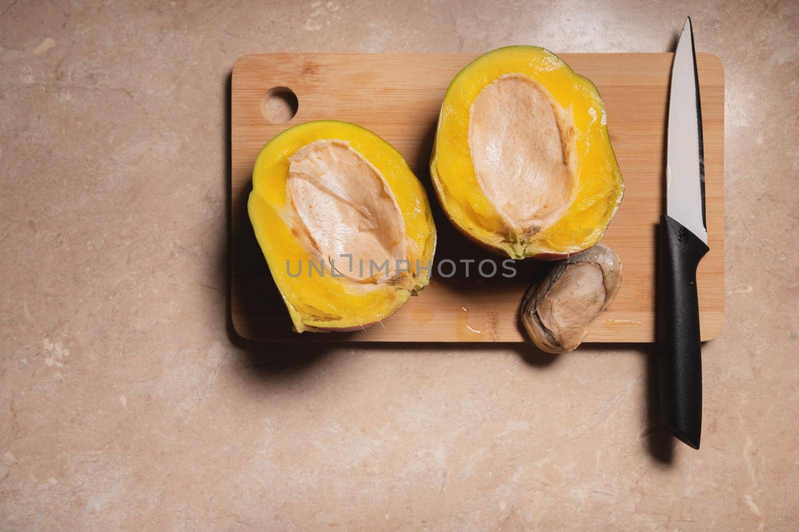 mango Kent in a cut on a wooden board on the table, next to it lies a bone and a knife