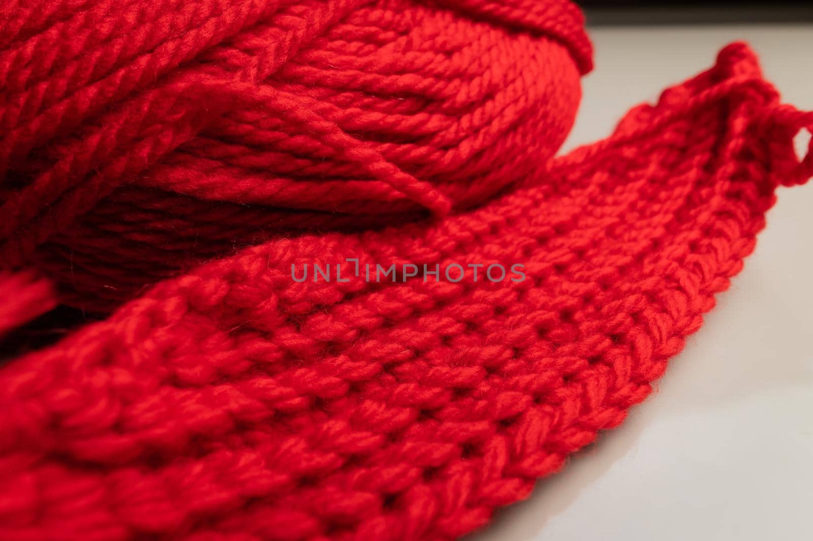 Close-up of an unknitted piece of wool next to a ball of yarn. Red wool yarn by yanik88