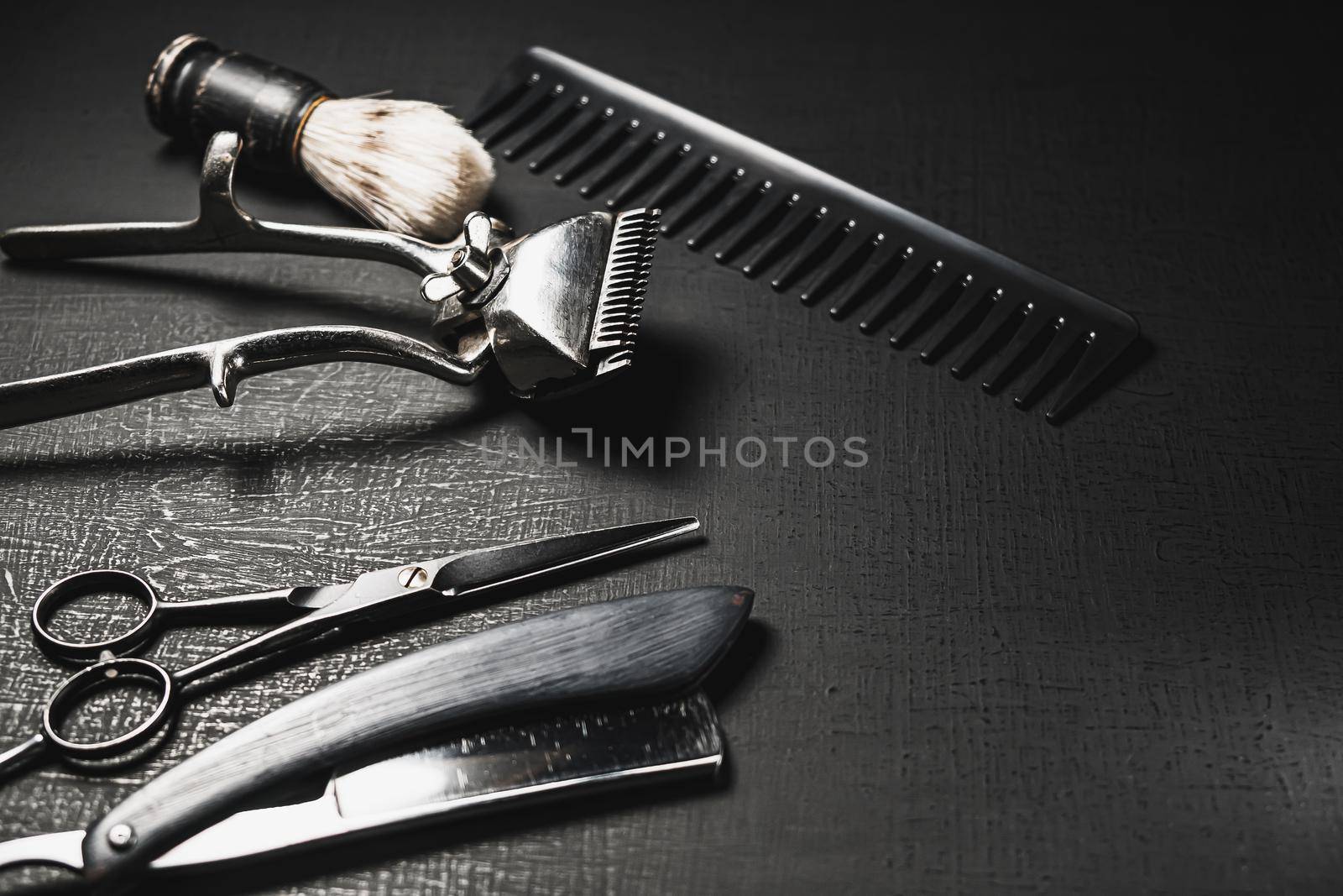 On a black surface are old barber tools. Vintage manual hair clipper comb razor shaving brush shaving brush hairdressing scissors. black monochrome. horizontal orientation. copy space