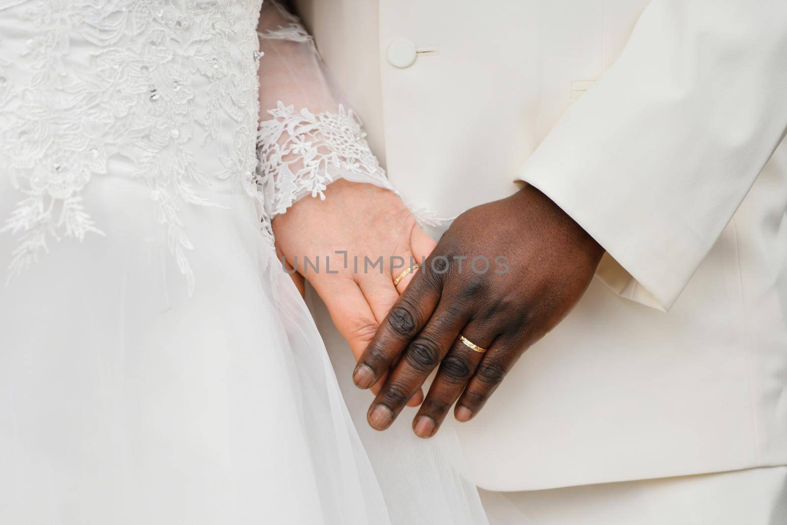 African and Causian couple holding hand with ring