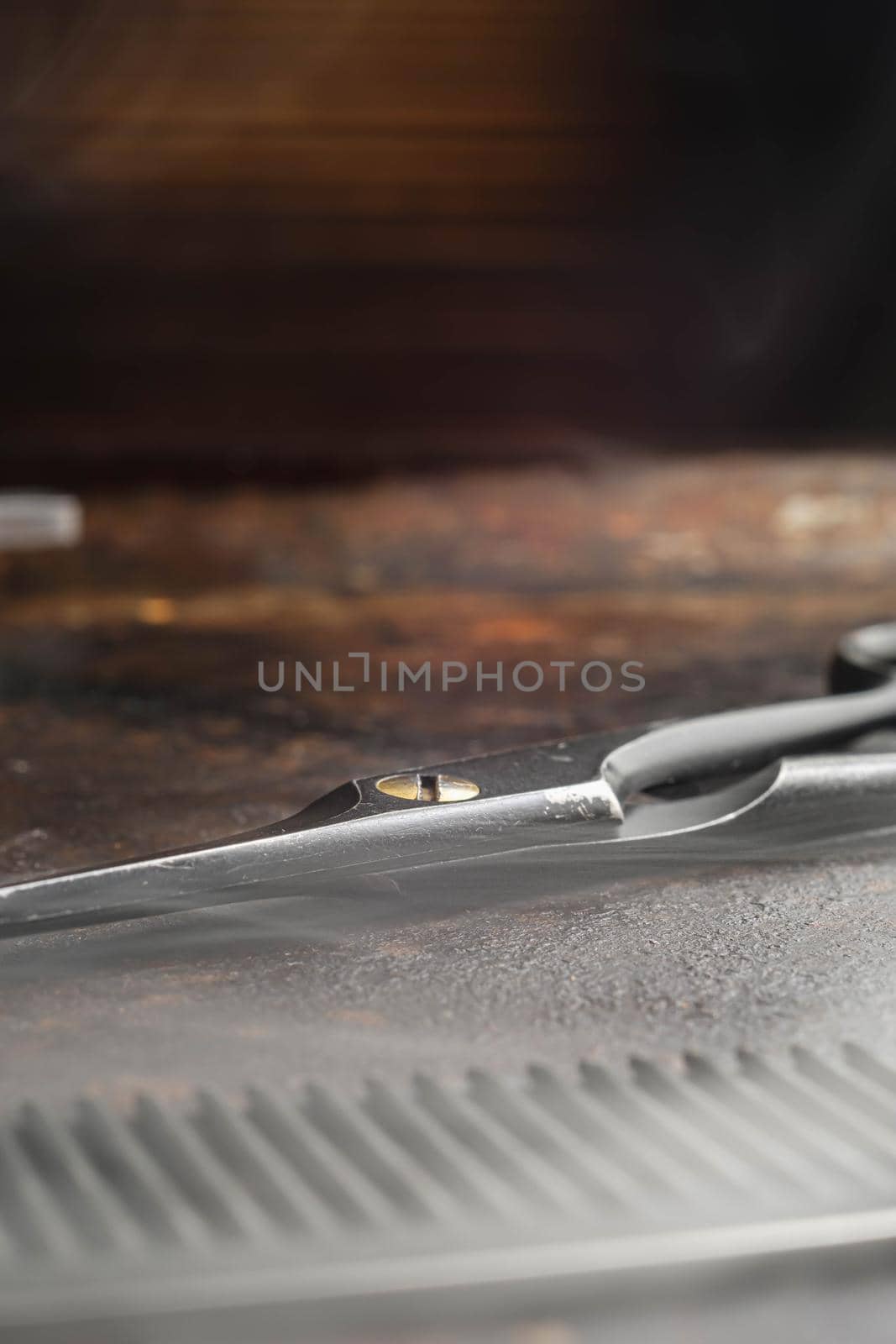 On a rusty surface hairdressing scissors and comb. close up. rustic.vertical orientation. copy space. steaming tools