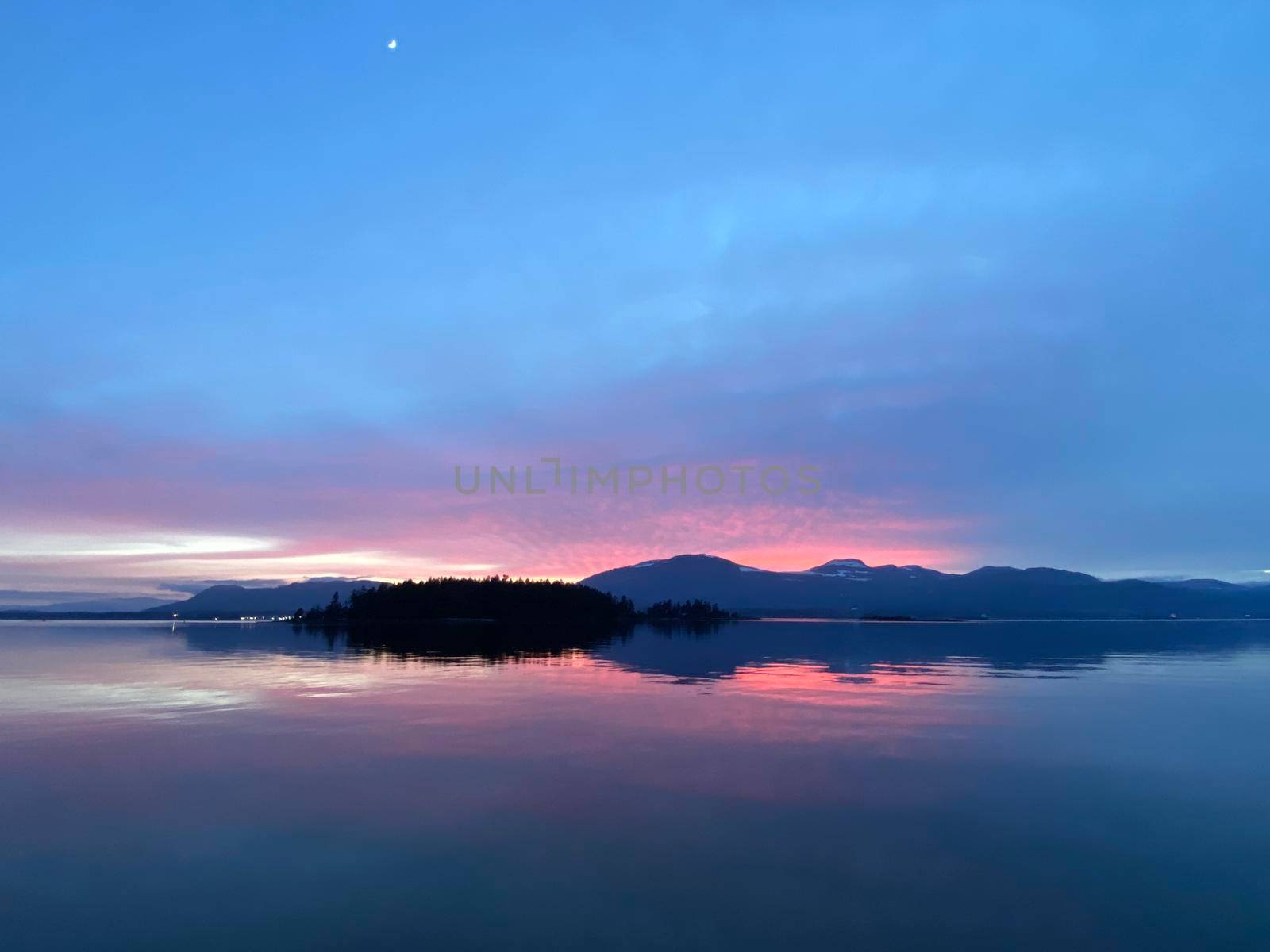 Beautiful pink sunset over mountains located on Vancouver Island with reflection onto water, Gulf Islands, British Columbia, Canada