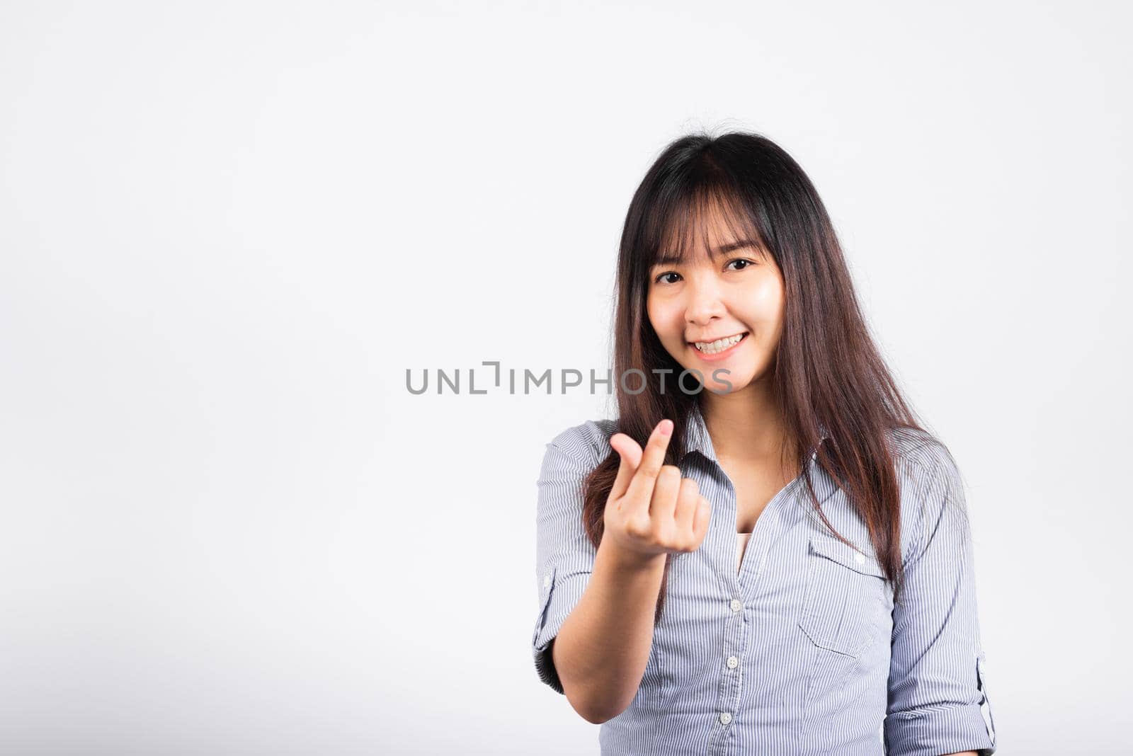 Woman standing her smile confidence showing mini heart sign with her finger isolated white background, Asian happy portrait beautiful young female send love and happy valentine in studio shot