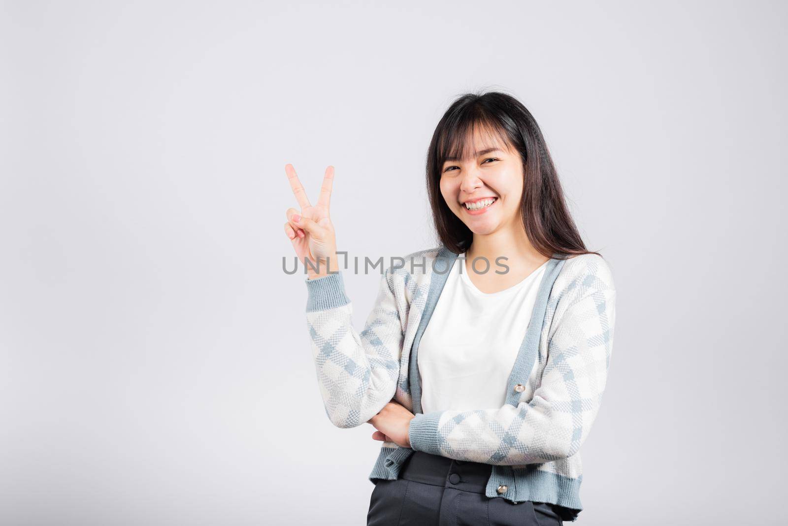 Woman showing finger making v-sign victory symbol side away looking to camera, Happy Asian beautiful young female mark peace gesture symbol, studio shot isolated on white background with copy space