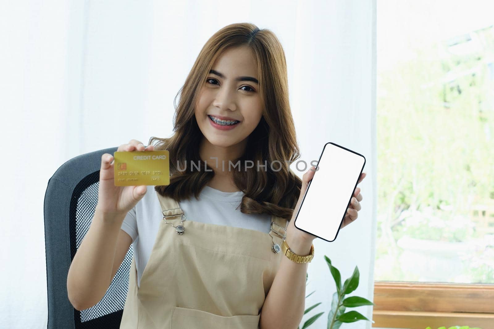 Young woman showing smartphone blank screen and credit card. Shopping online and Online payment concept by itchaznong