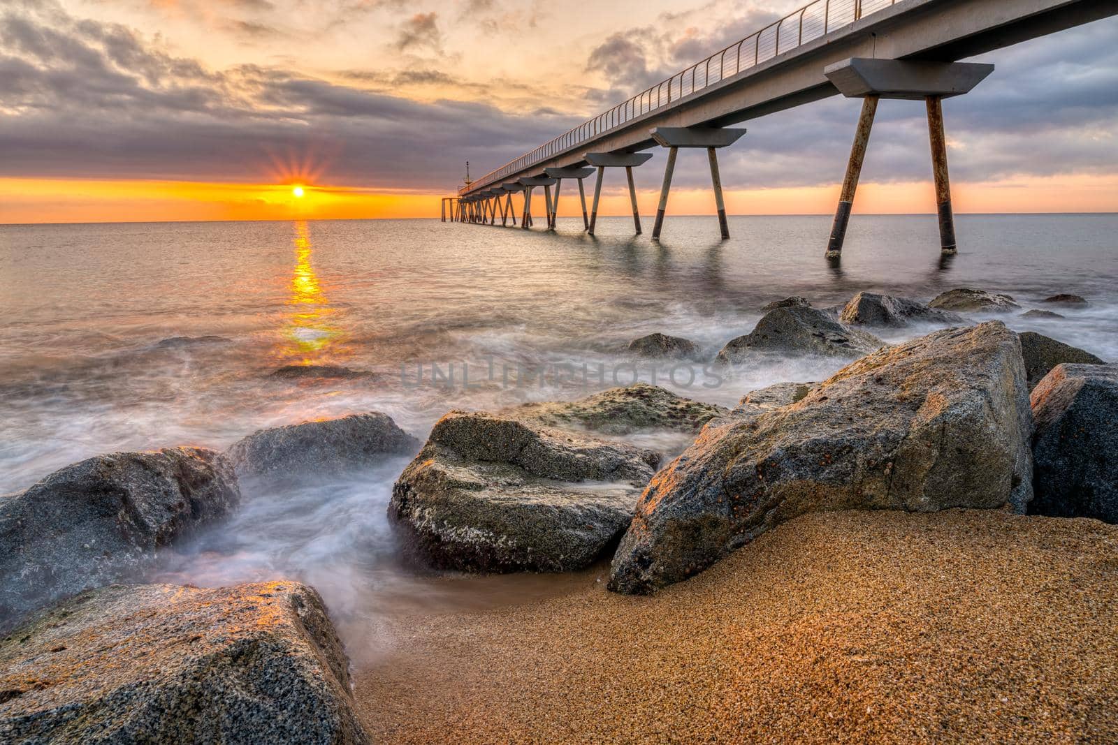 The sea pier of Badalona at sunrise by elxeneize