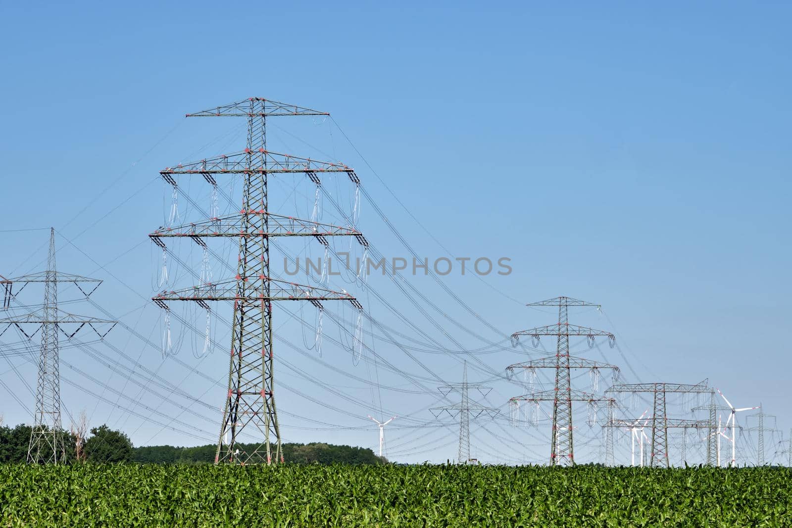 Electricity pylons and power lines with wind turbines in the back seen in Germany