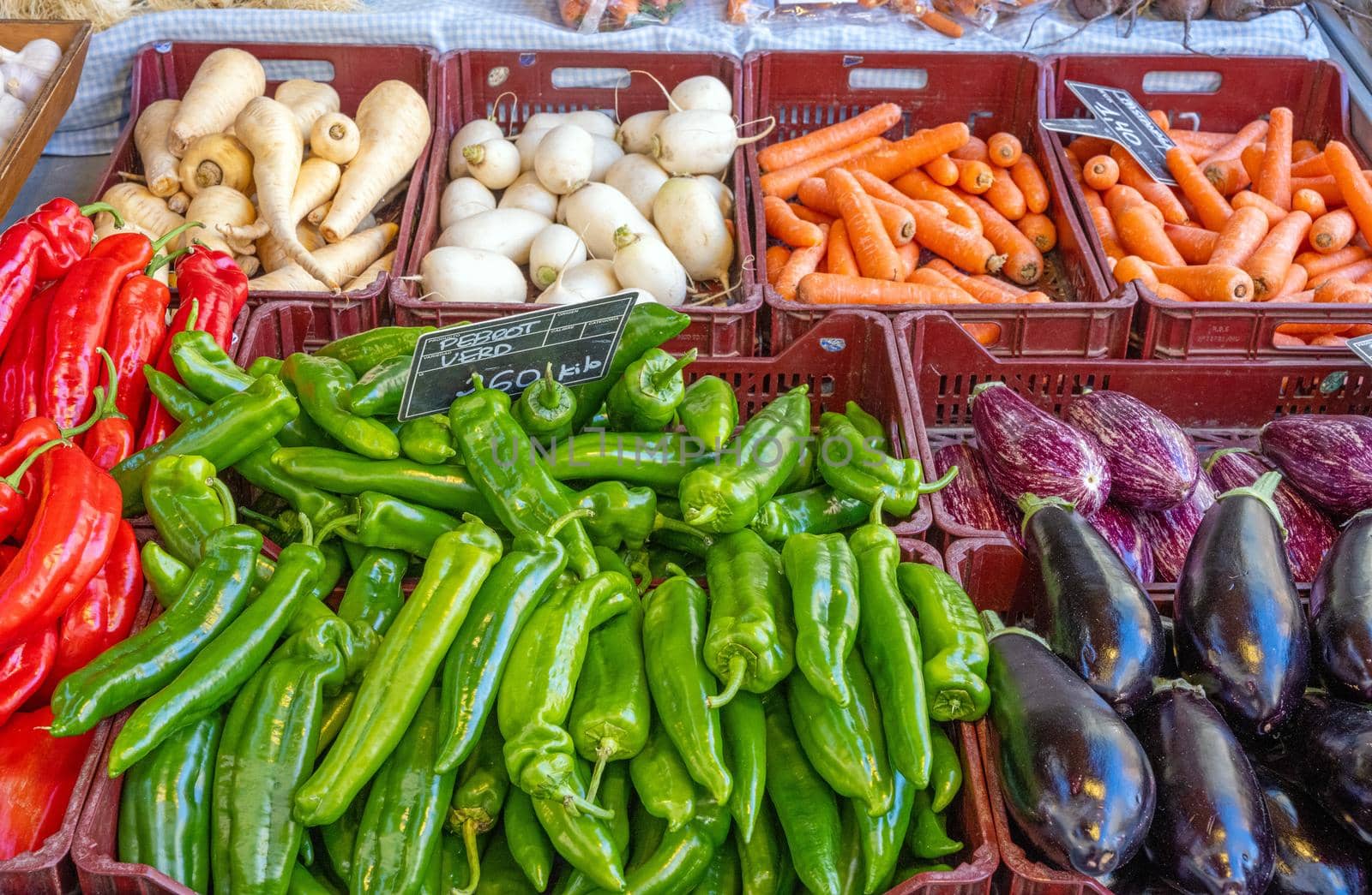 Different kinds of bell pepper and aubergines for sale at a market