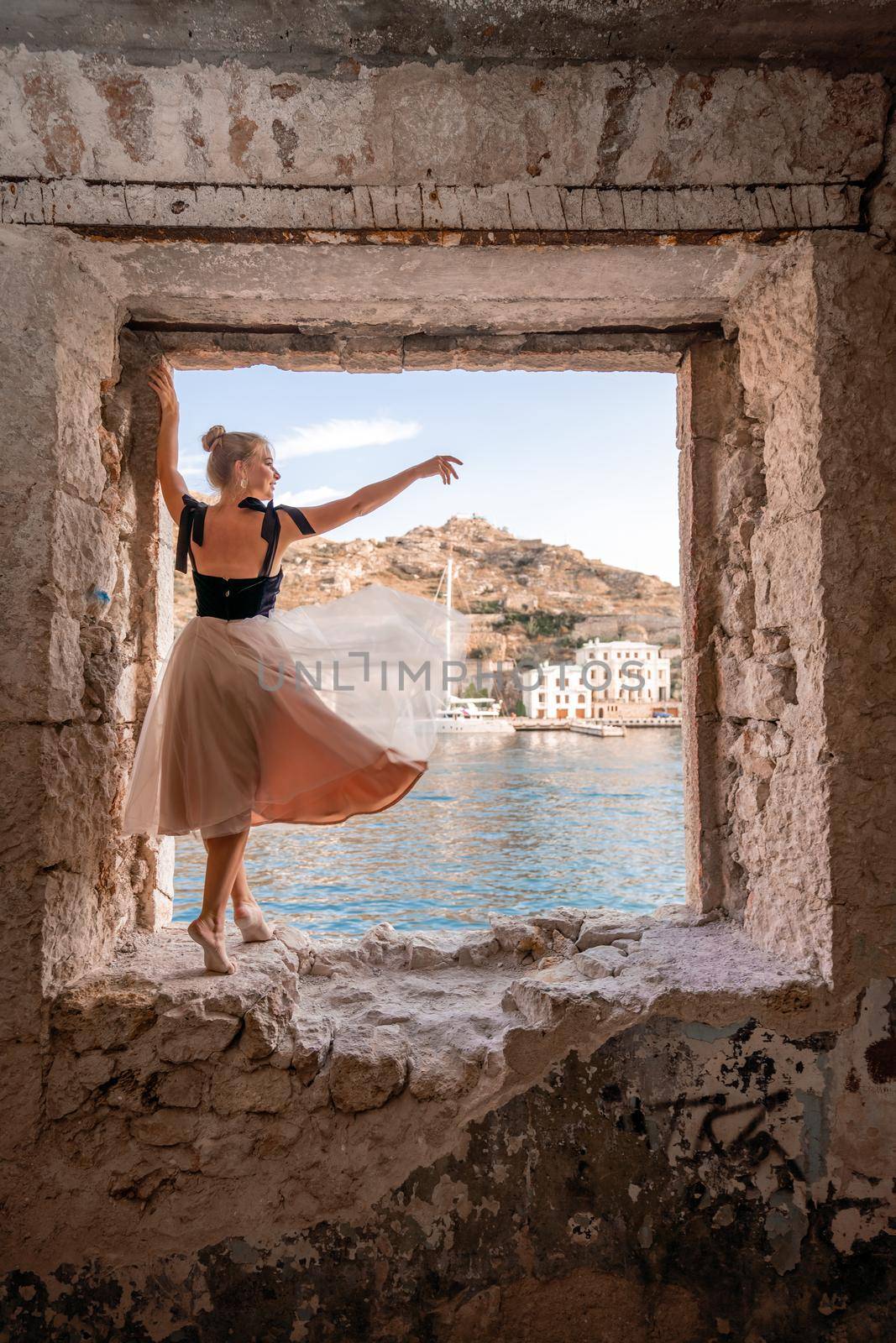 Side view portrait of a relaxed woman breathing fresh air at the seaside. She stands on the window in the old building