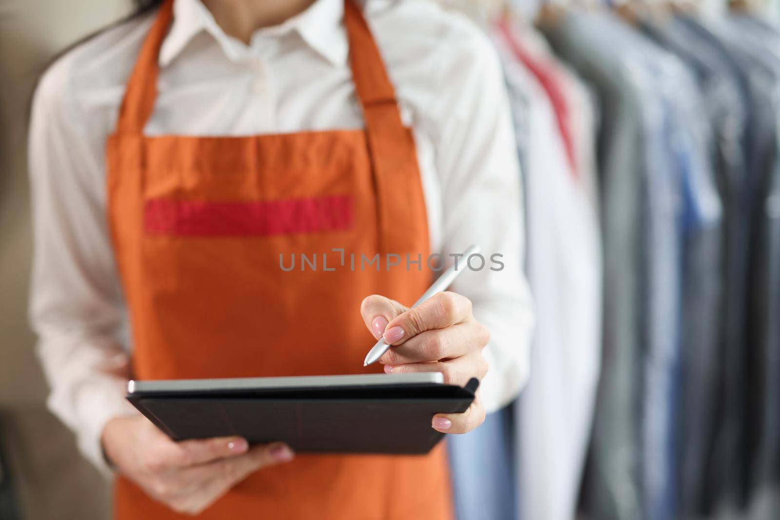 Woman laundry worker makes notes, close-up, blurry. Reception, storage and delivery of washed linen in dry cleaning