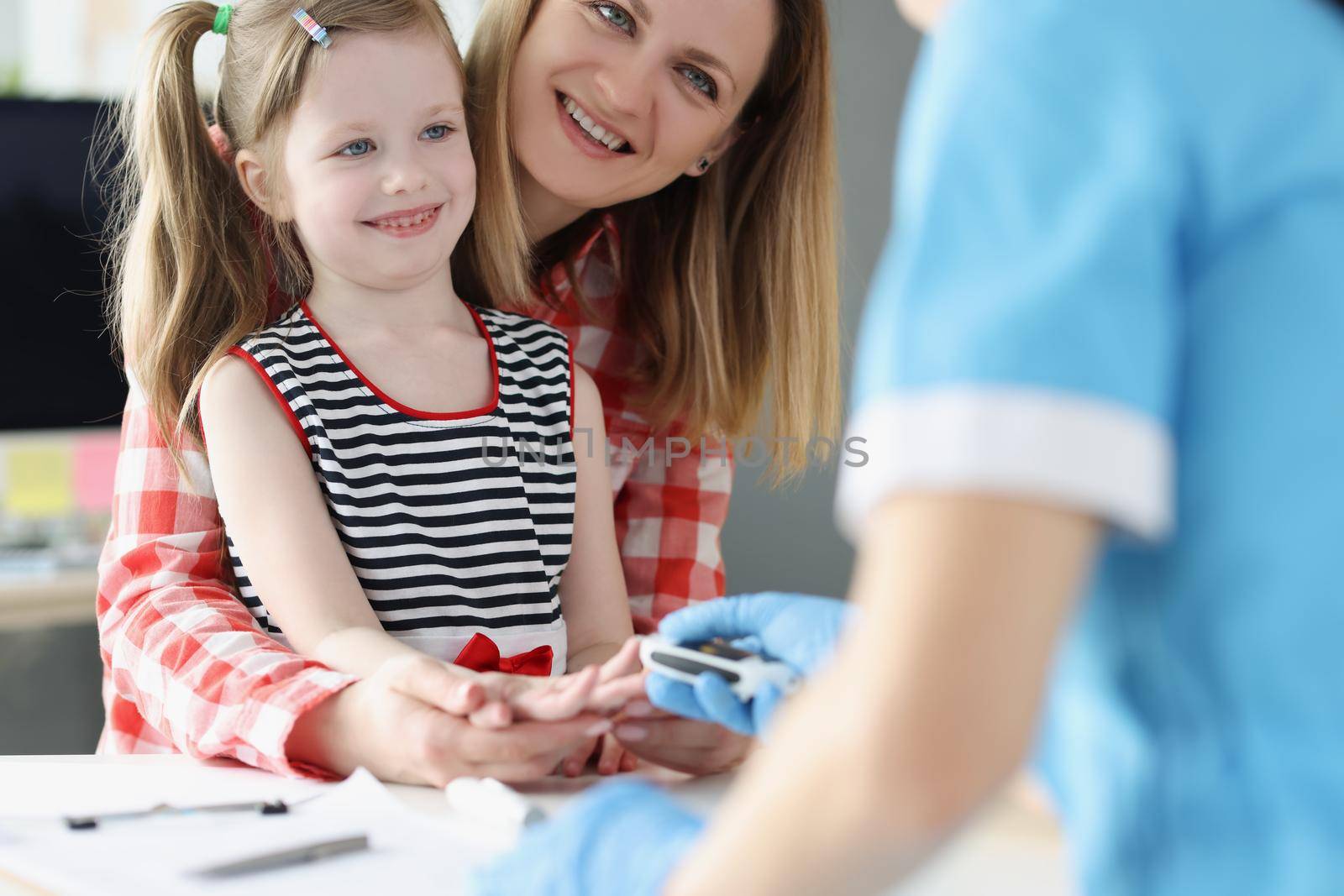 A nurse takes a blood test from a finger of a little girl by kuprevich