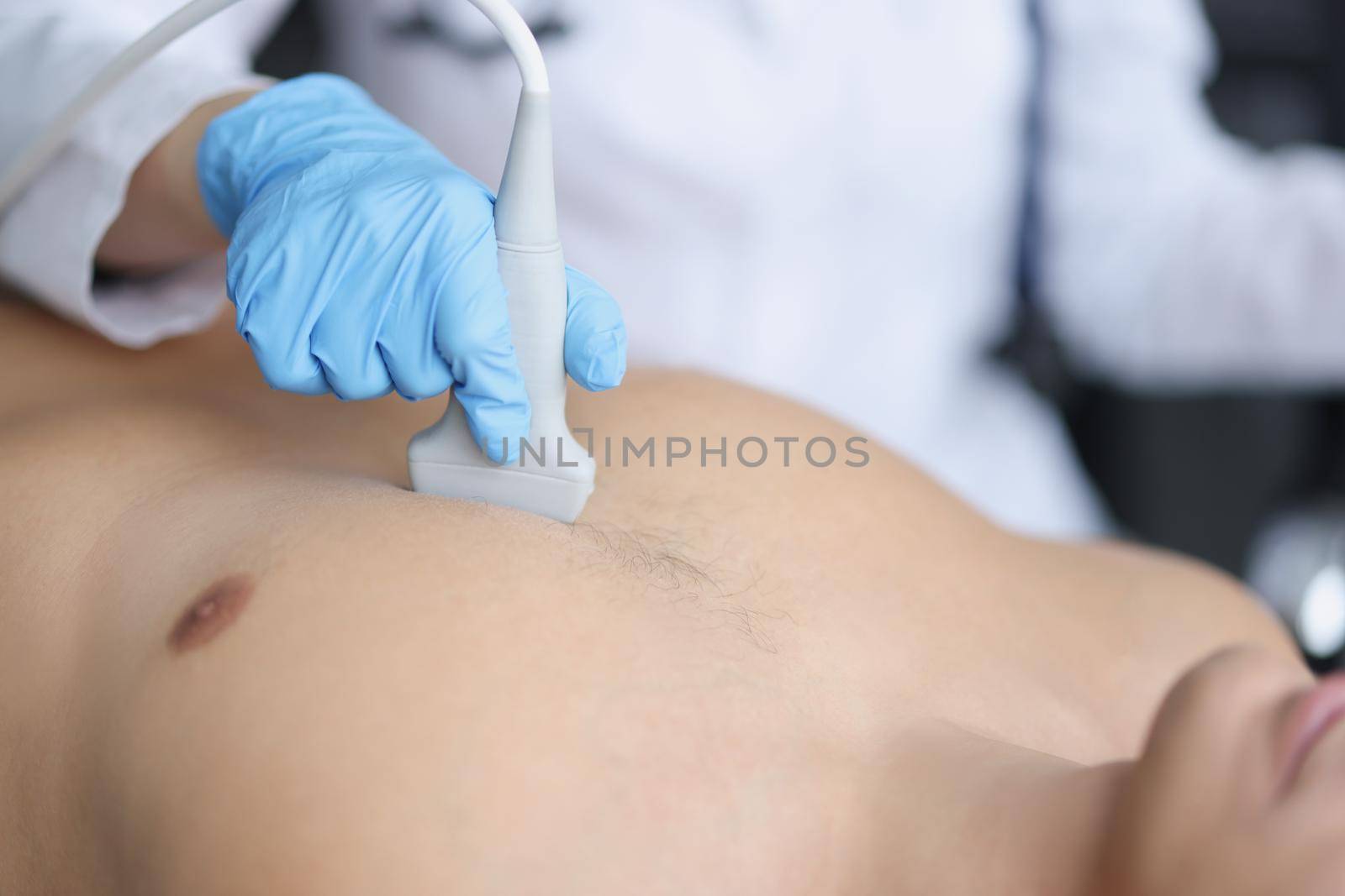 Doctor's hands on the chest of a man, ultrasound of the heart, close-up. Diagnosis of diseases of the cardiovascular system