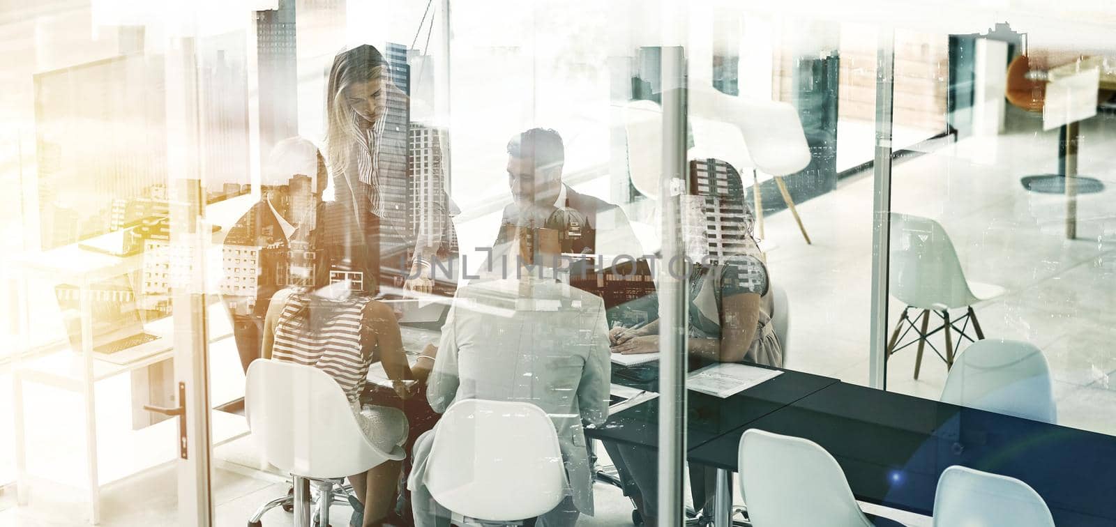 Multiple exposure shot of businesspeople in an office superimposed on a cityscape