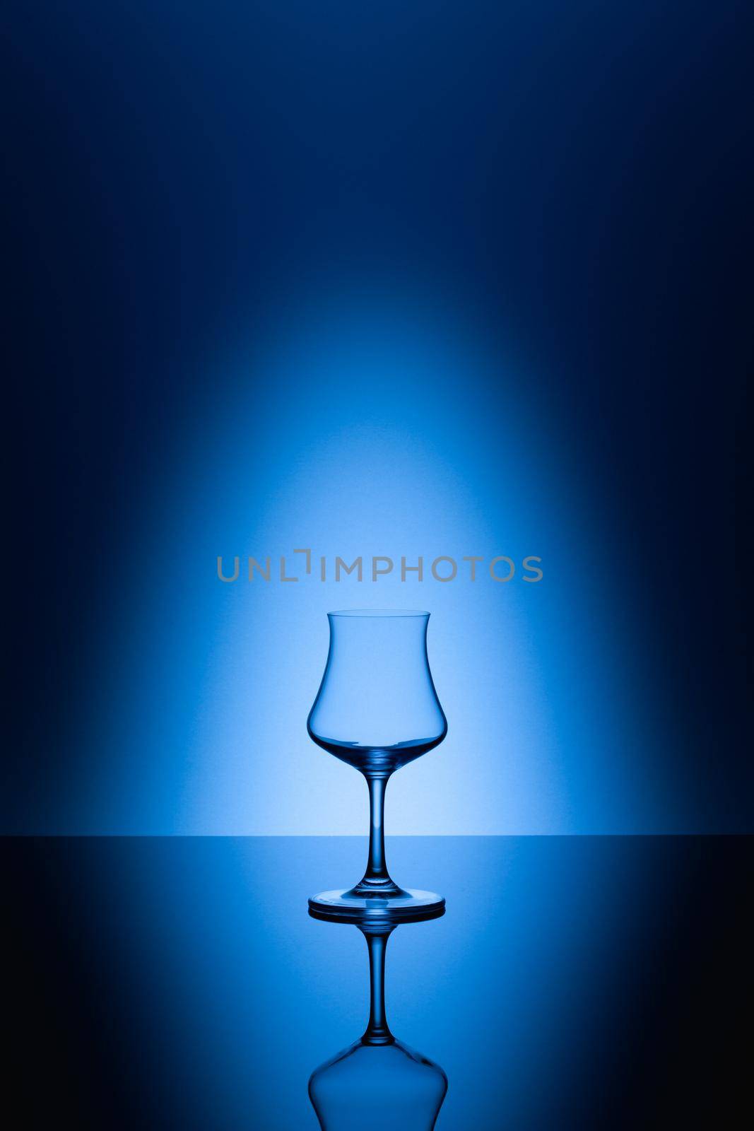 Rum tasting glass on the glass table and blue background
