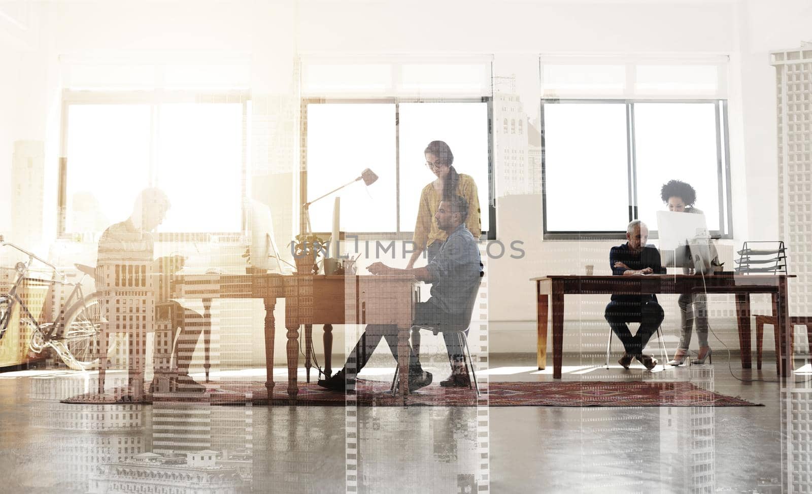 Multiple exposure shot of colleagues working in a modern office superimposed over a city background