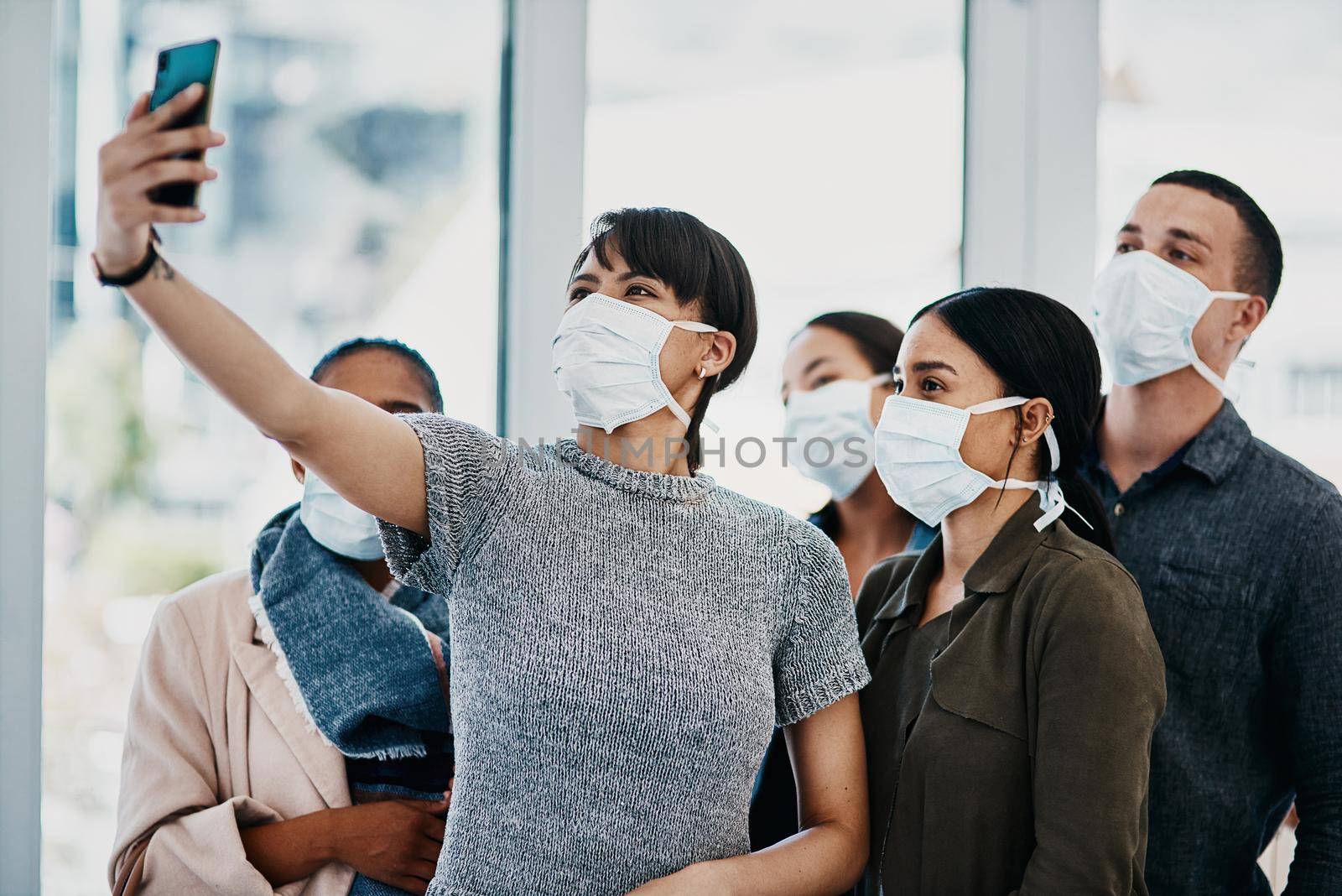 Shot of a group of young people wearing masks and taking selfies at the airport