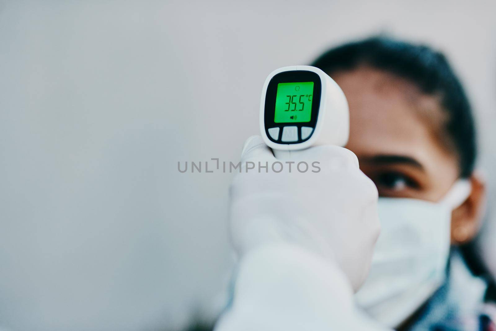 Cutting edge tech to help curb the spread. Shot of a young woman getting her temperature taken with an infrared thermometer by a healthcare worker during an outbreak. by YuriArcurs
