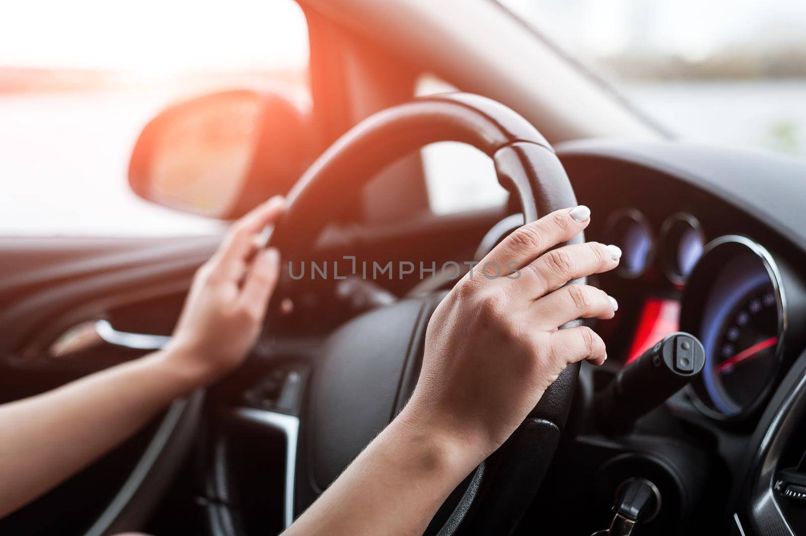 Women's hands on the steering wheel, inside the car. Taken in close-up, in the car.