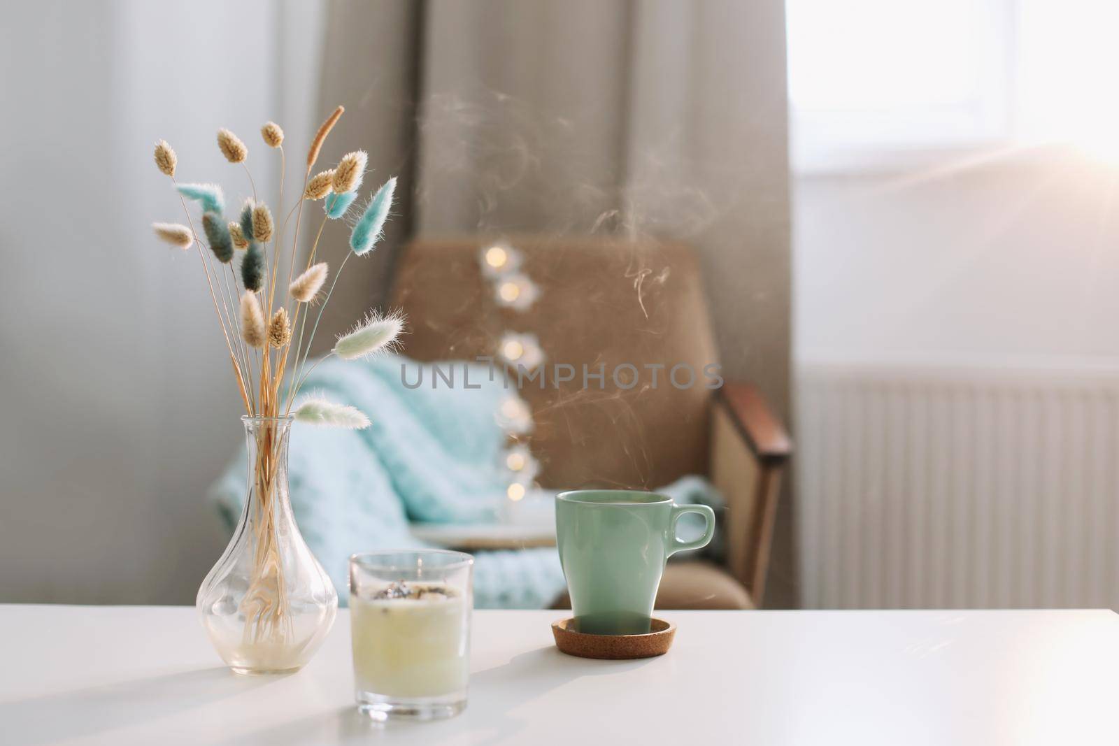 Cup of coffee and a transparent vase with dried flowers at white background. 