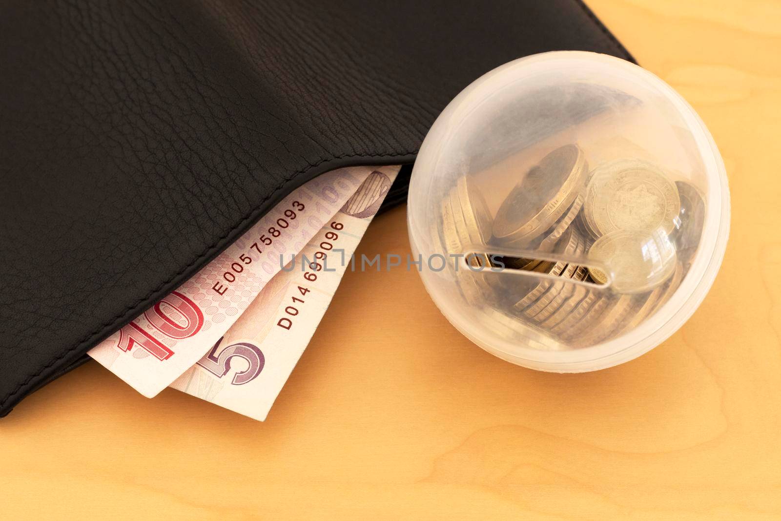 budget is limited. only some cash is in a wallet and coins are on a wooden table