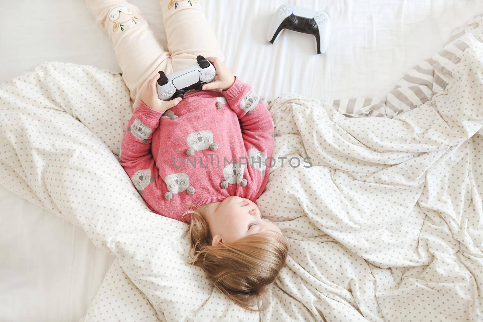 Little cute girl playing with joystick in bed at home