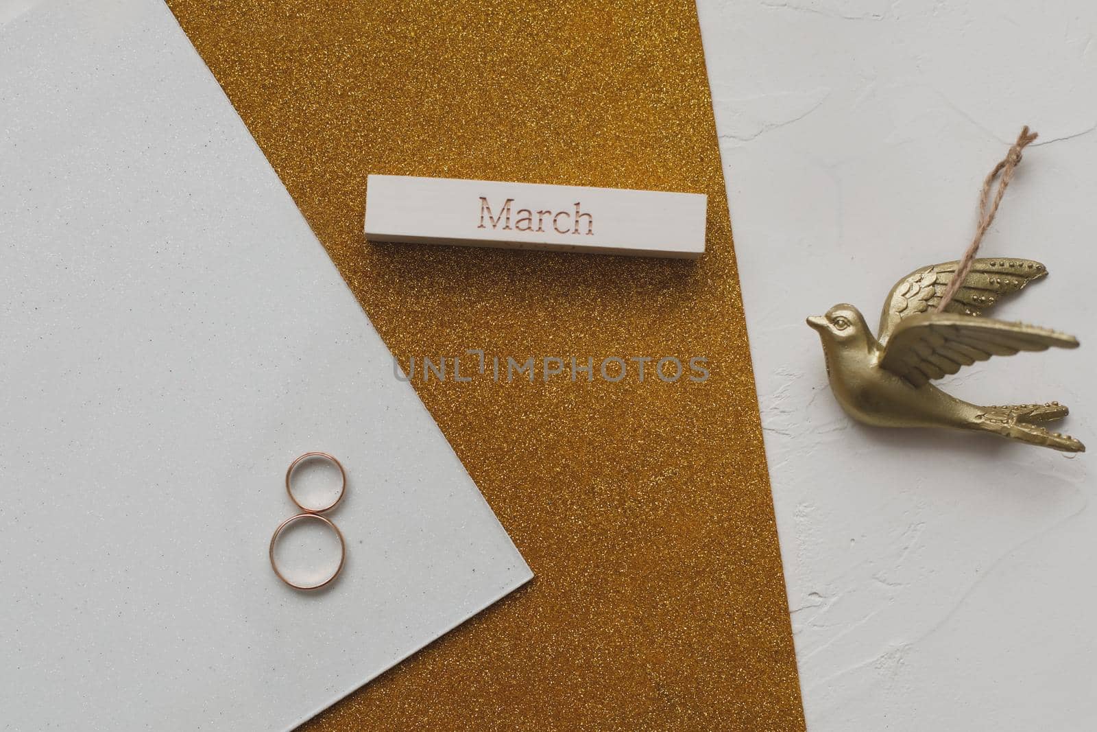 8 March, International Women's Day background with decor elements. Eight made of two gold wedding rings and word MARCH. Greeting card for March 8. Flat lay, top view, copy space