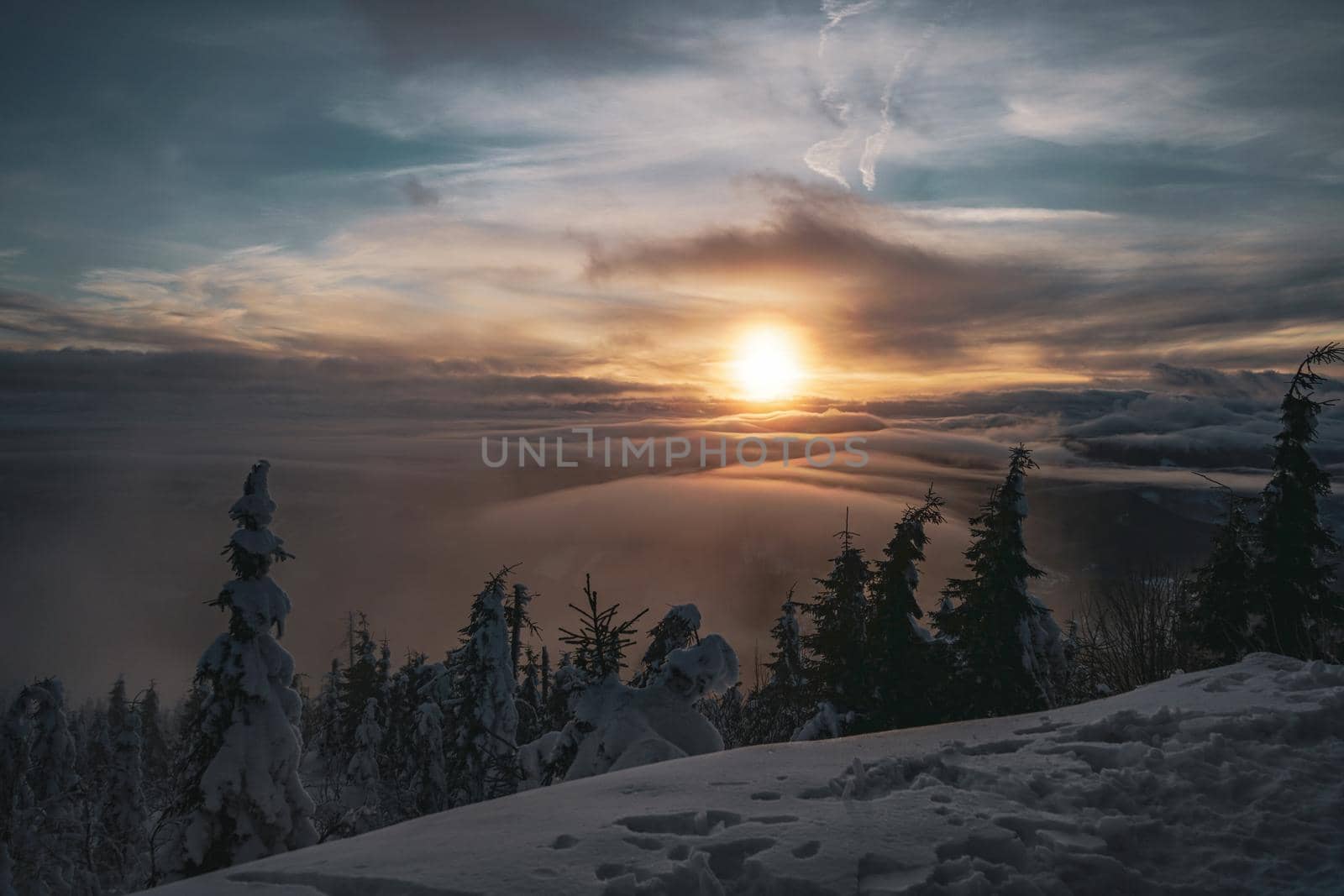 Dramatic Sunset with Trees and Low Clouds View Landscape from Mountain Peak with deep snow by Skrobanek
