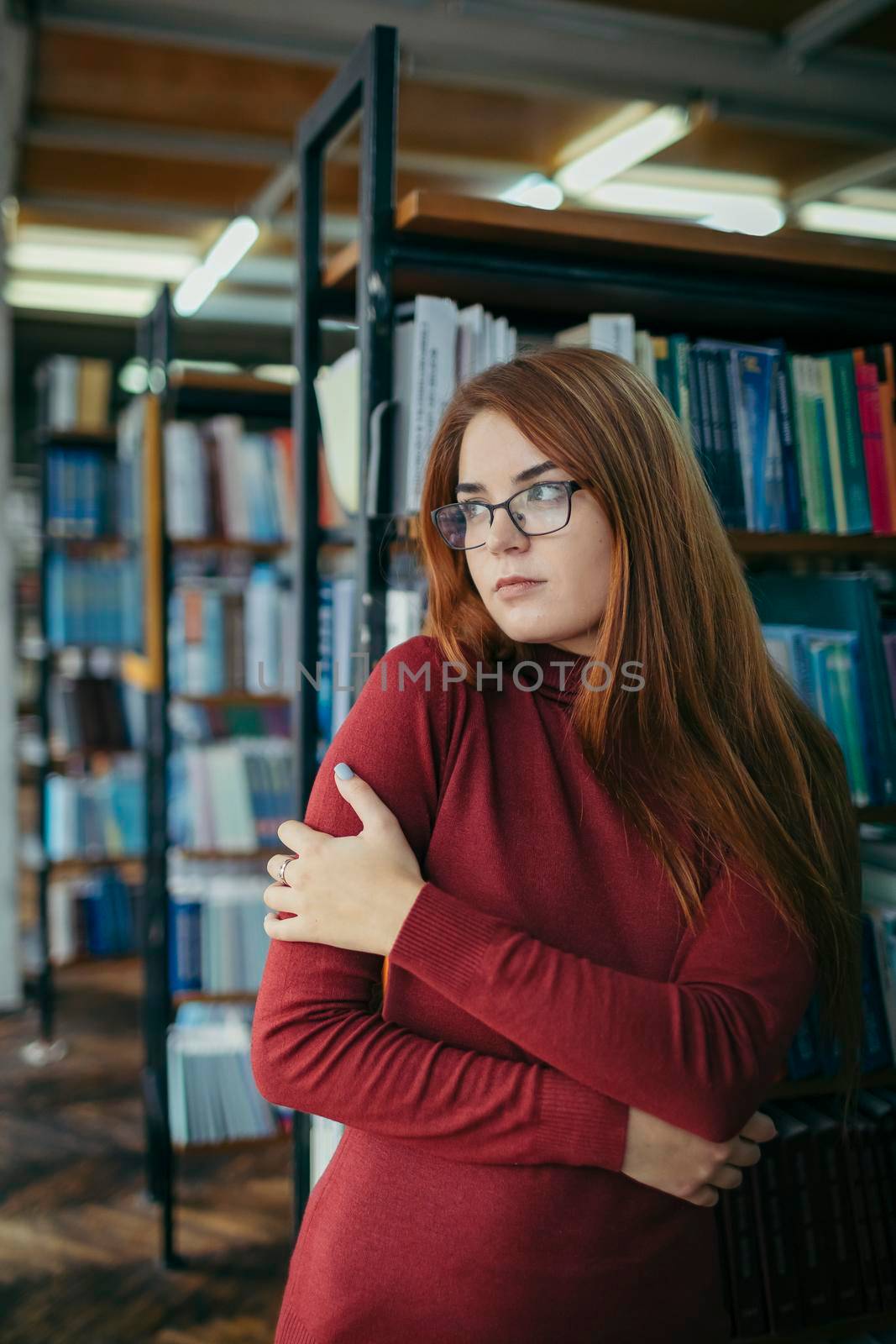 A girl holding a book shelf. High quality photo. Student in the library