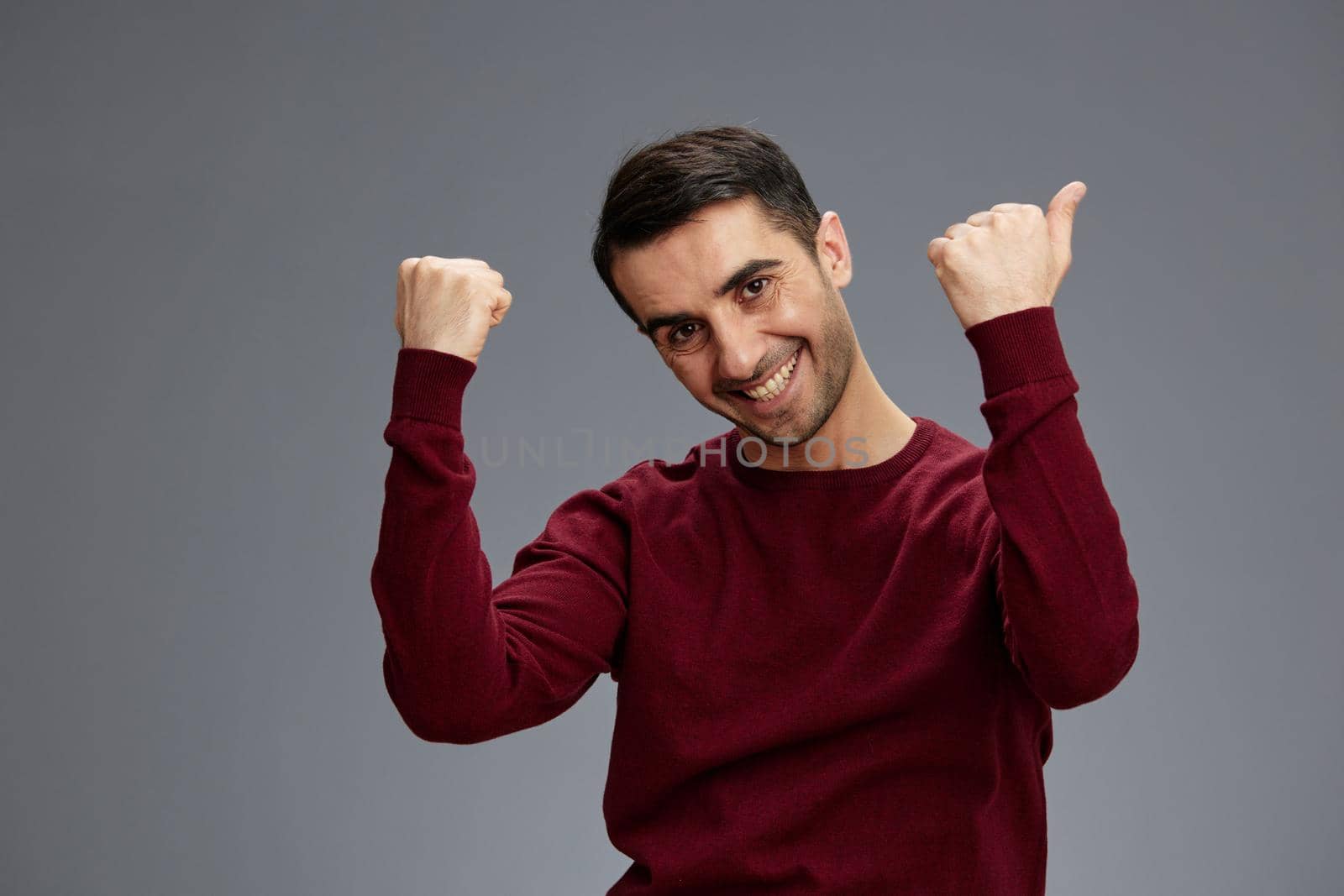 portrait man pointing fingers to the side in a sweater posing hand gesture emotions Gray background. High quality photo
