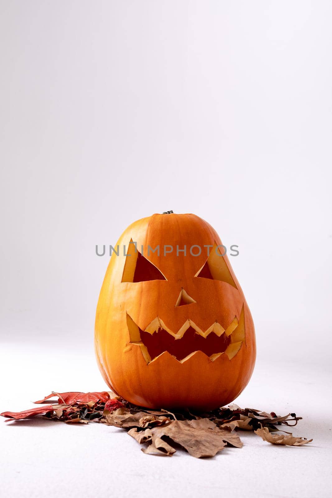Composition of halloween jack o lantern, leaves and copy space on white background. horror, fright, halloween tradition and celebration concept digitally generated image.