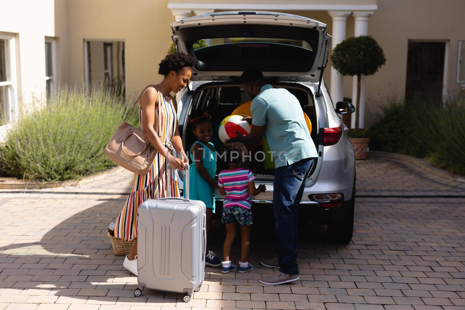 African american family loading luggage and ball in car trunk while going for picnic by Wavebreakmedia