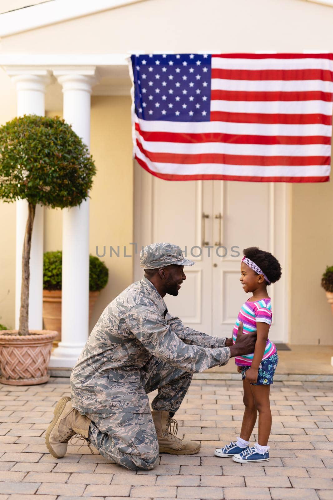 African american male soldier kneeling and greeting daughter at house entrance by Wavebreakmedia