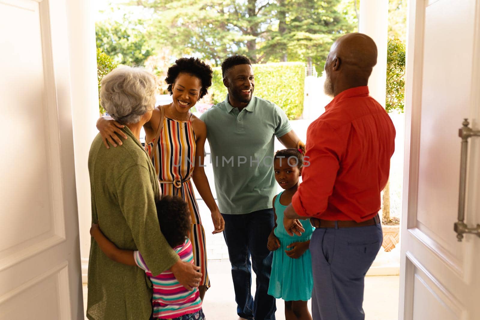 African american senior couple welcoming their family while standing on the front door at home. family, love and togetherness concept, unaltered.