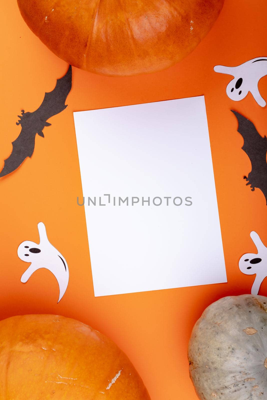 Composition of halloween decoration with pumpkin and sheet with copy space on orange background. halloween tradition and celebration concept digitally generated image.