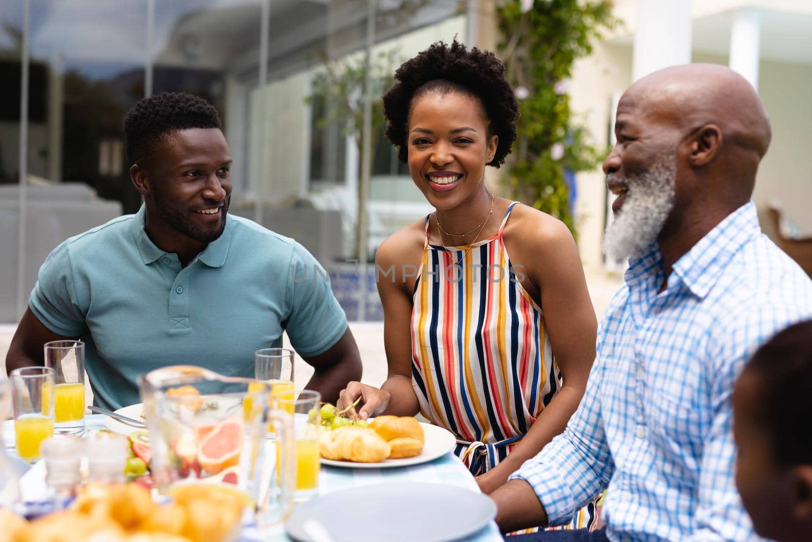 Portrait of smiling african american woman enjoying brunch with family at backyard. family, love and togetherness concept, unaltered.