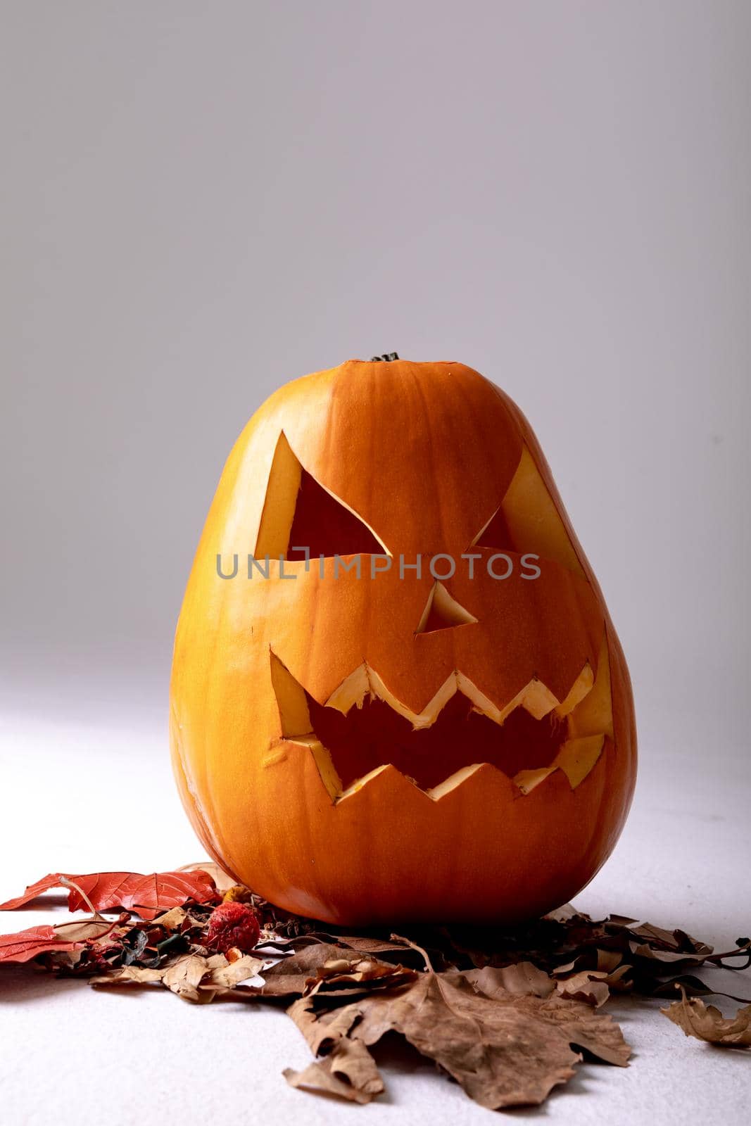 Composition of halloween jack o lantern, leaves and copy space on grey background. horror, fright, halloween tradition and celebration concept digitally generated image.