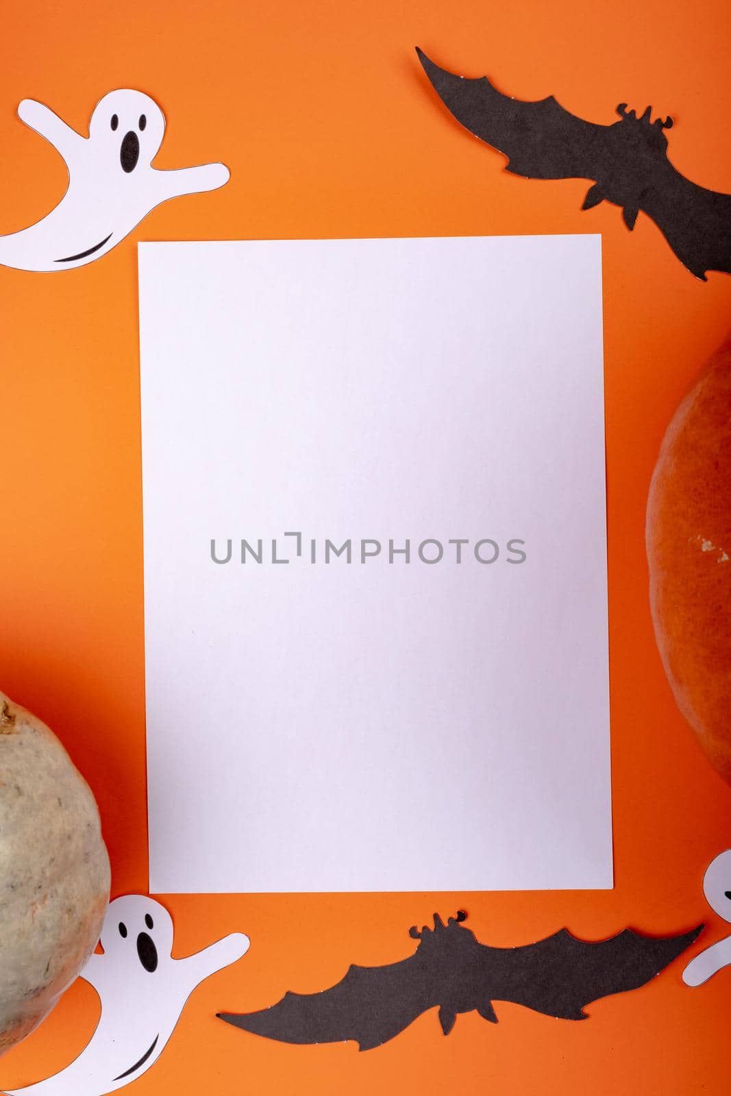 Composition of halloween decoration with ghost, bat and sheet with copy space on orange background. halloween tradition and celebration concept digitally generated image.