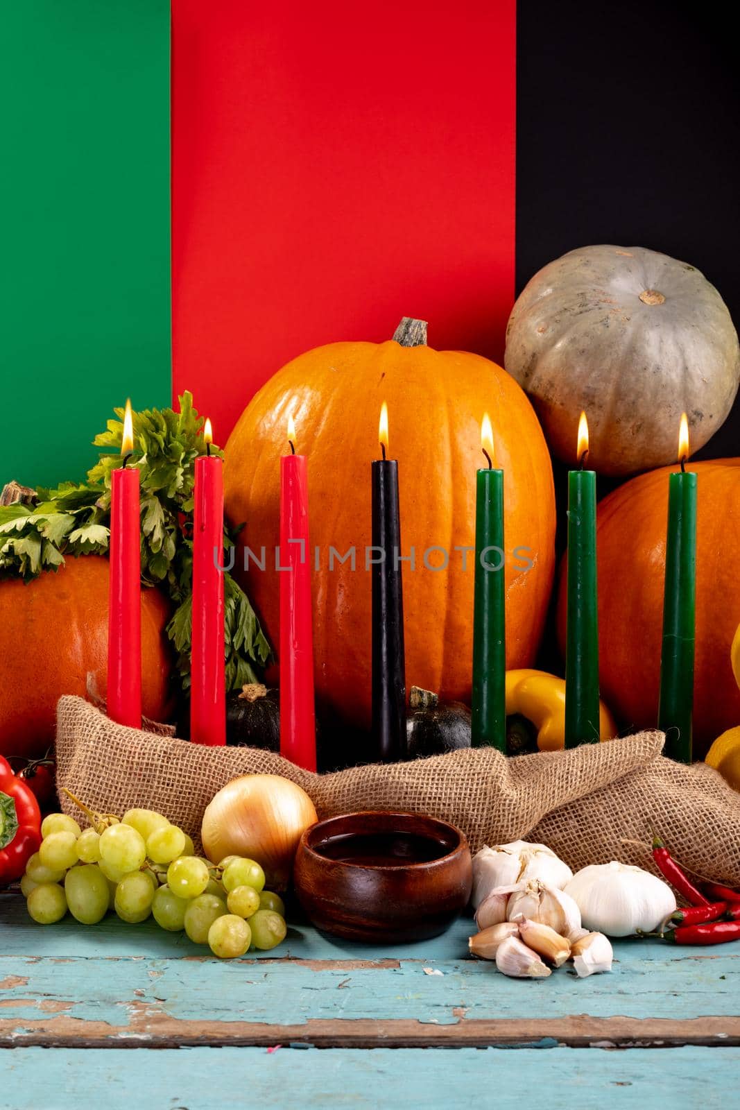 Composition of halloween decoration with candles and pumpkins on tricoloured background. horror, fright, halloween tradition and celebration concept digitally generated image.