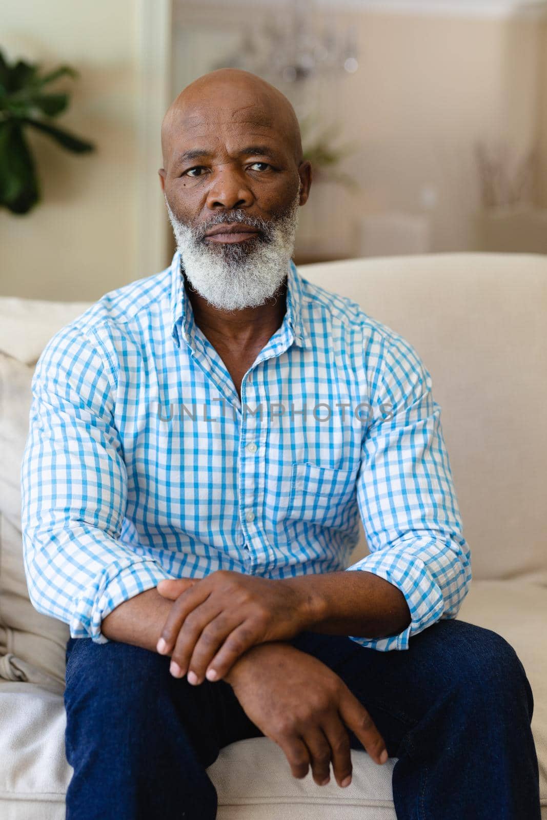 Portrait of african american senior man sitting on couch at home by Wavebreakmedia