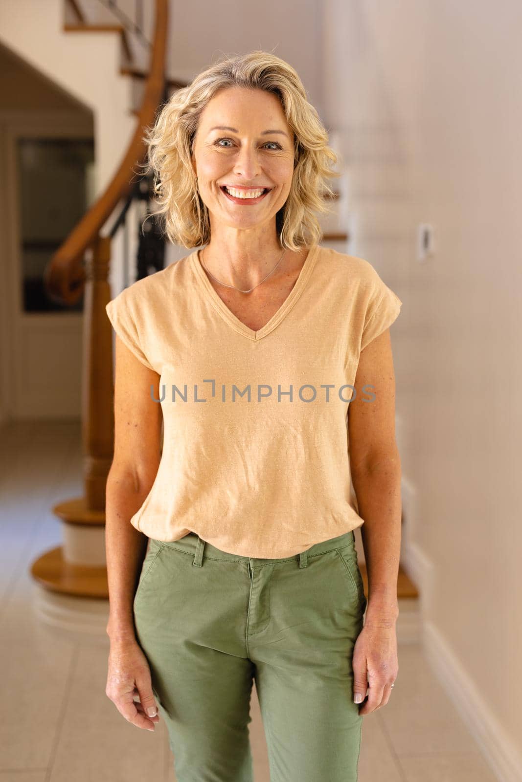 Portrait of caucasian senior woman smiling while standing in the living room at home by Wavebreakmedia