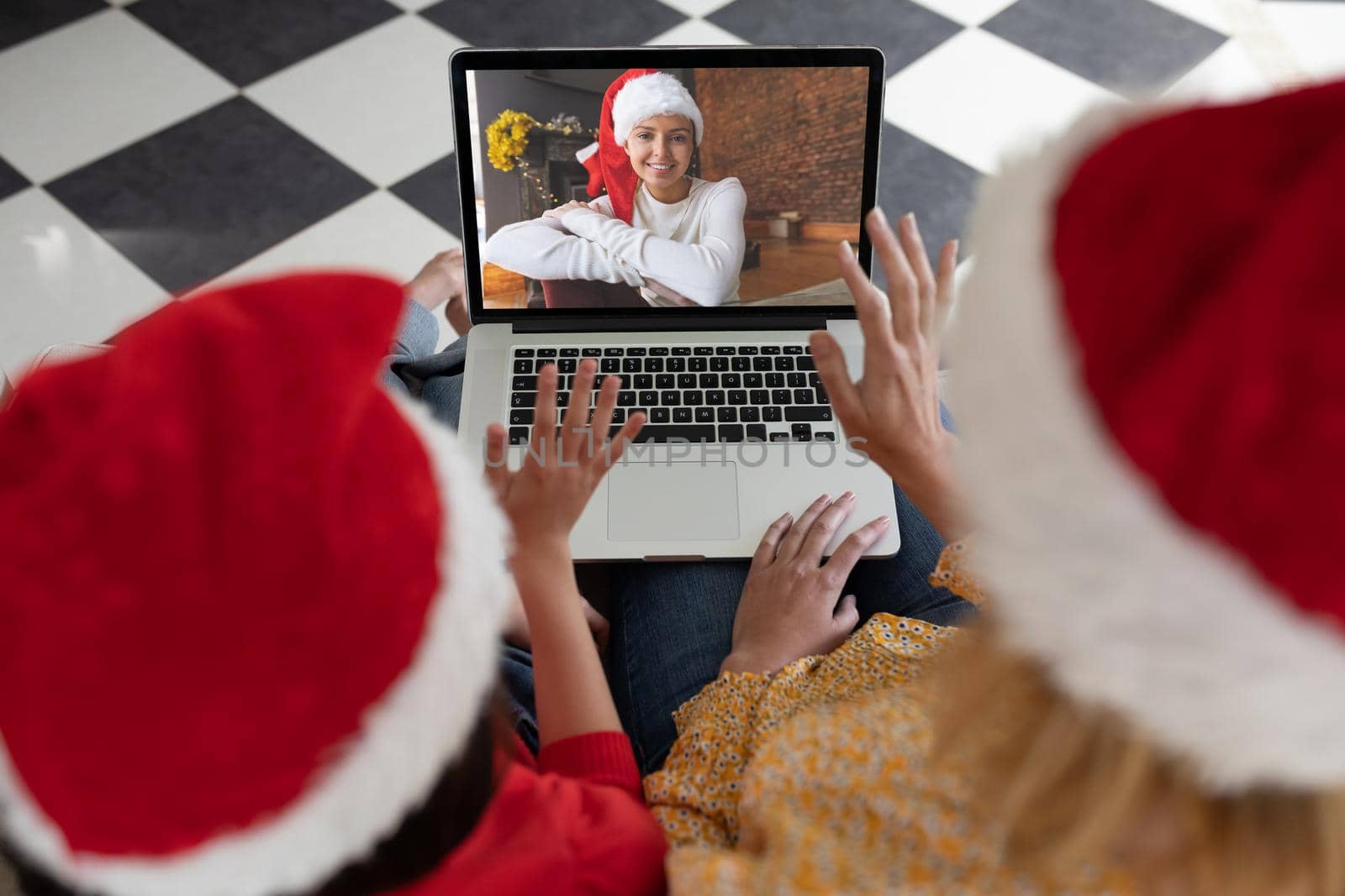 Caucasian woman with her daughter at home at Christmas, using laptop computer, video chatting with a by Wavebreakmedia