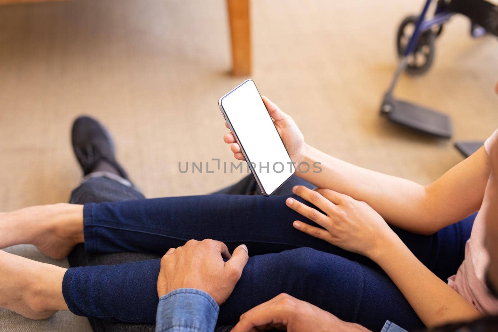 High angle view of young biracial couple using smartphone with copy space on blank screen at home by Wavebreakmedia