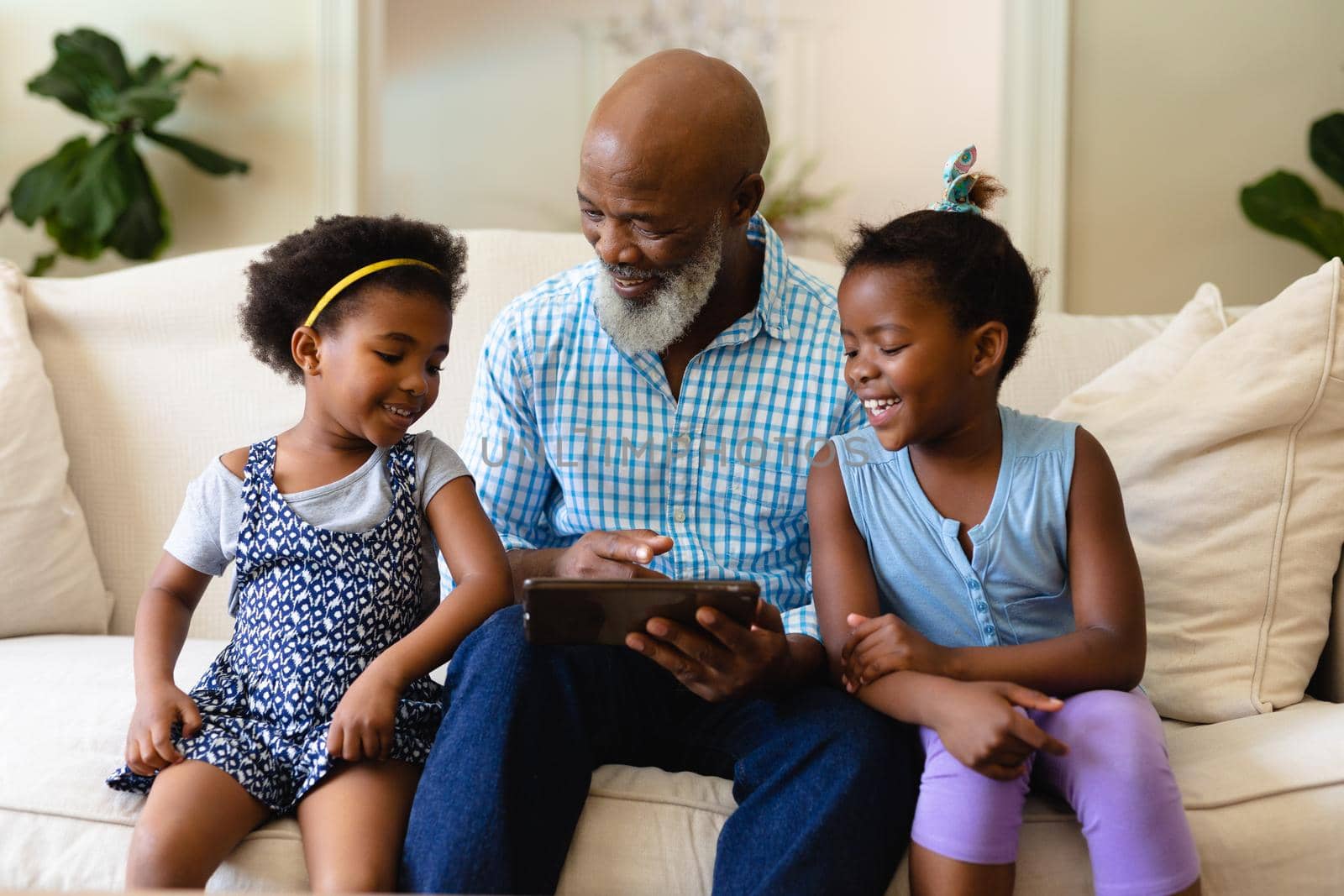 Smiling african american girls with african american grandfather showing digital tablet. unaltered, wireless technology, family, lifestyle, childhood, leisure activity, and domestic life concept.